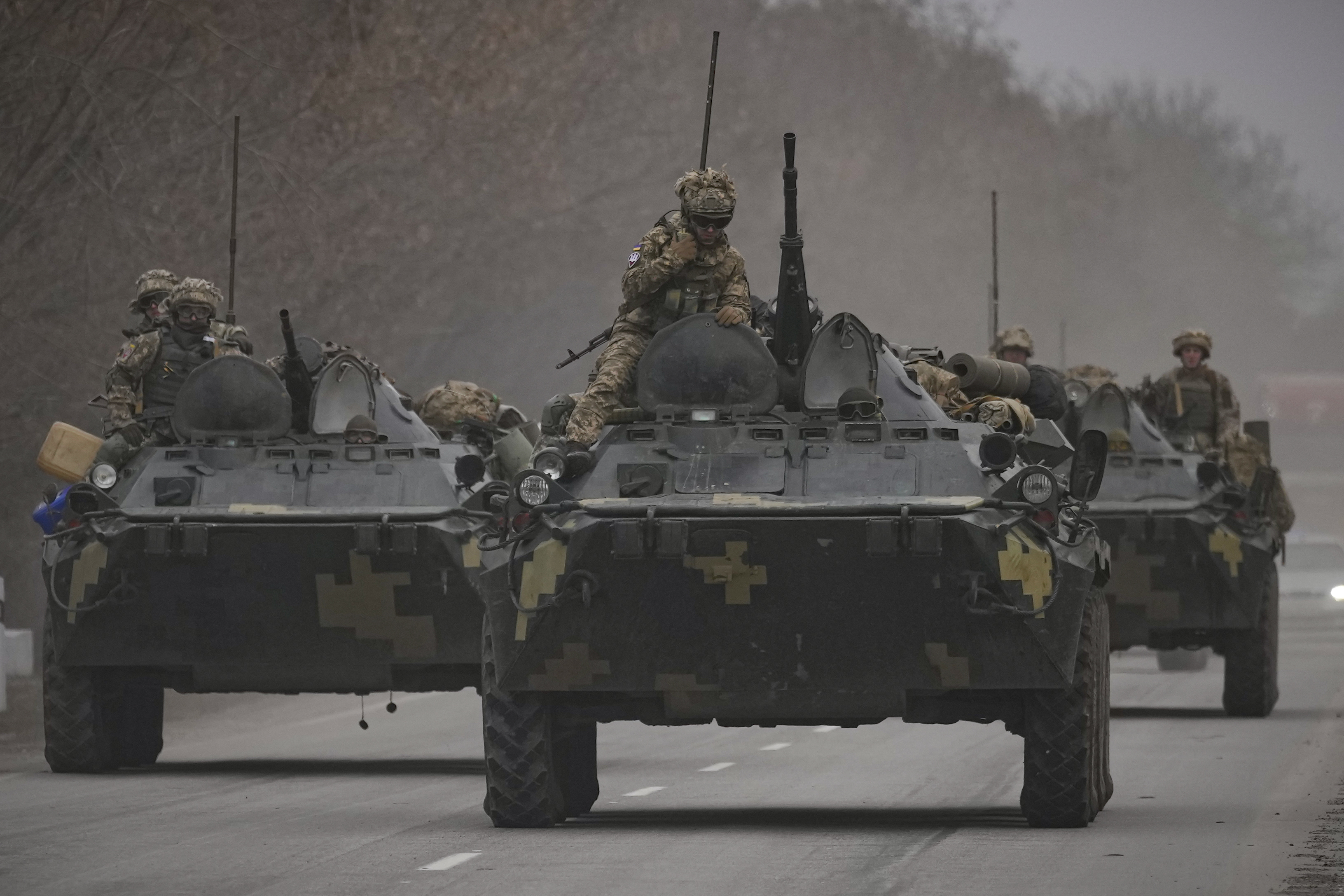 Ukrainian servicemen sit atop armored personnel carriers driving on a road in the Donetsk region, eastern Ukraine