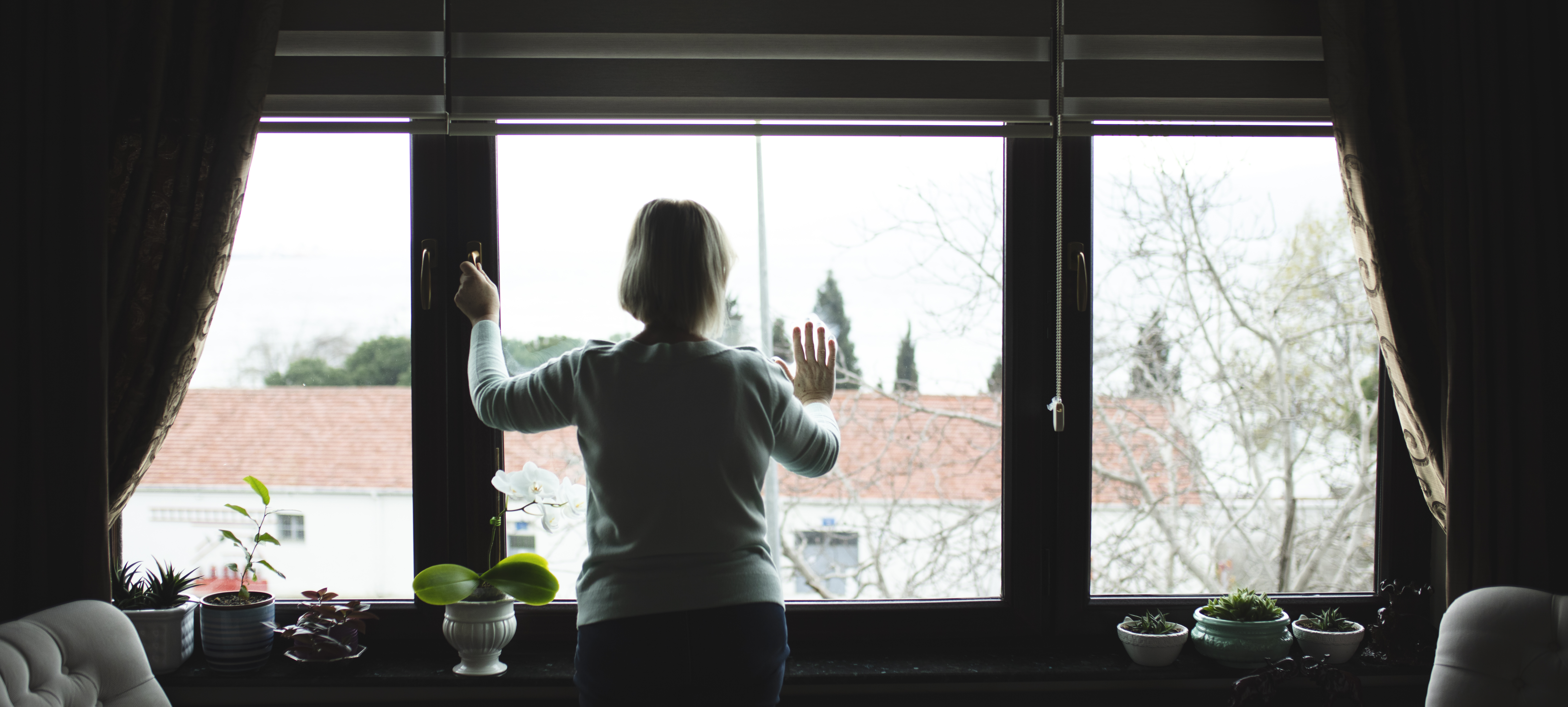 Women in COVID-19 isolation looking outside the window