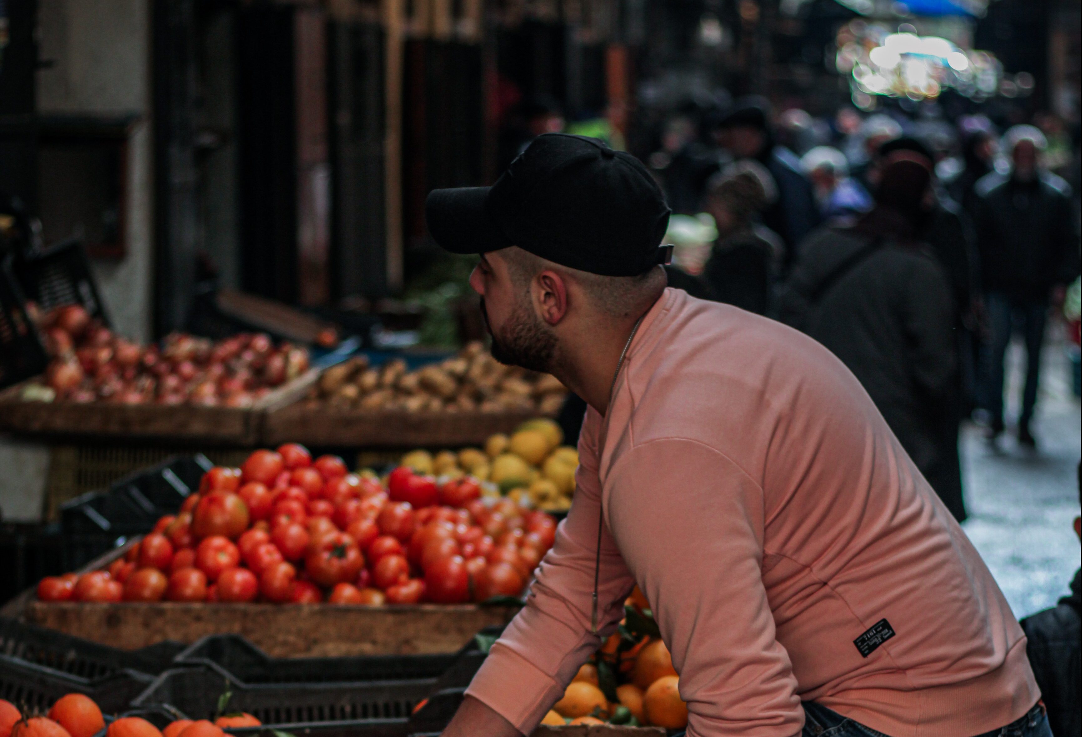 Young men rests his leg onto a basket filled with oranges at the fruit and vegetable market in Tripoli, Lebanon.