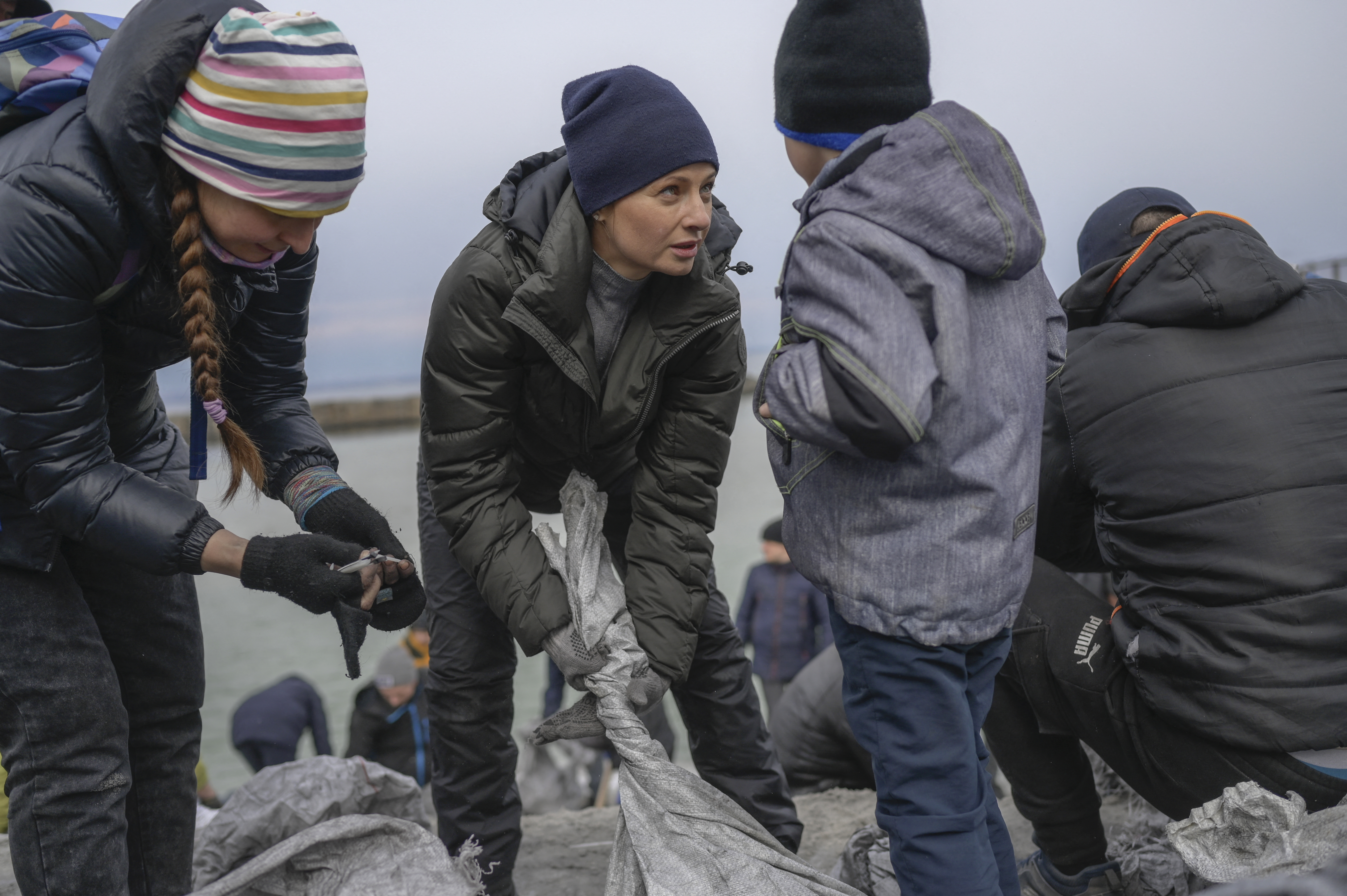 A woman from Odessa talks to her son as they fill bags with sand for frontlines, along the beach of the Black Sea city of Odessa