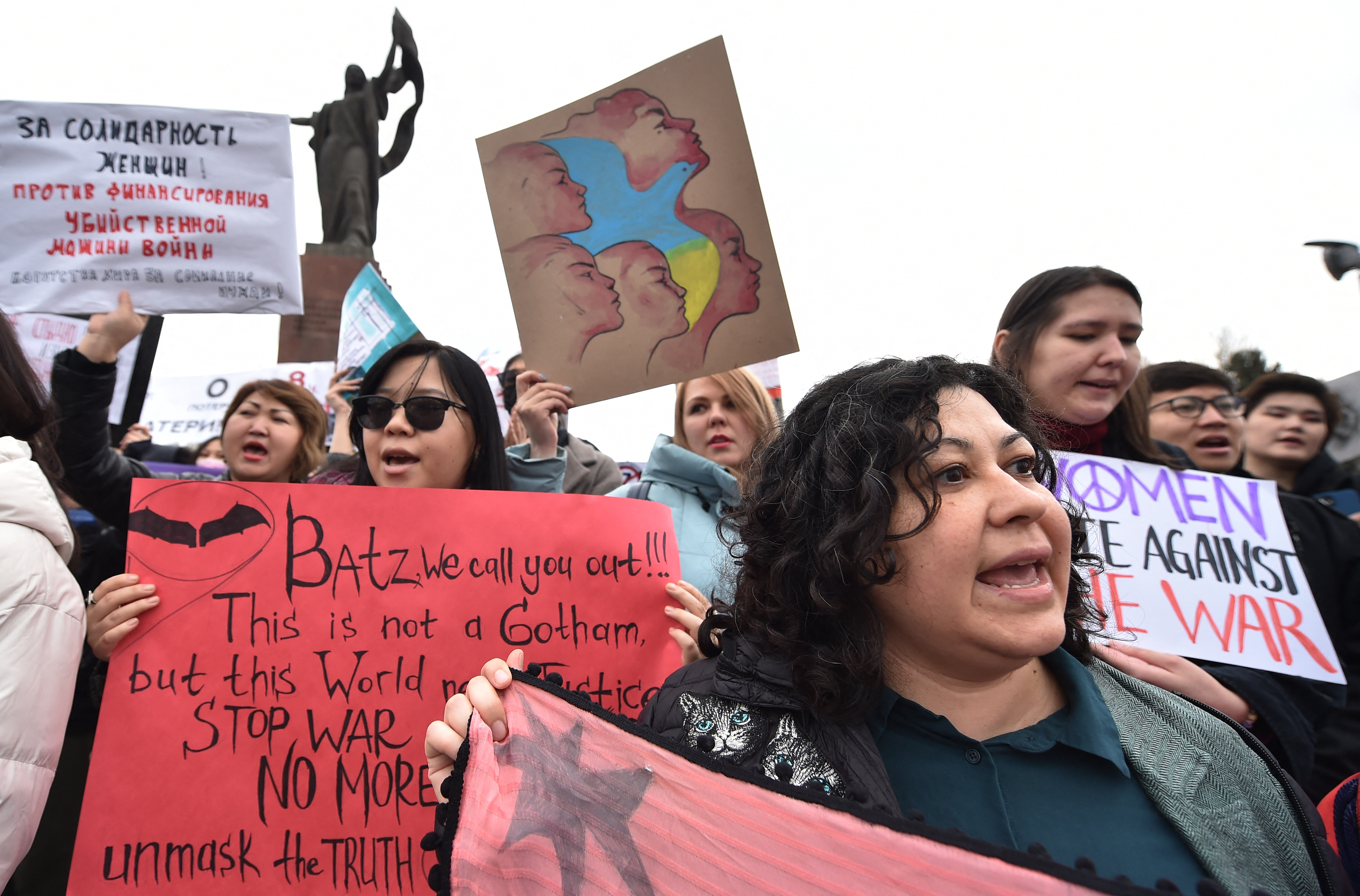 People carry banners and posters, some denouncing Russia's invasion of the Ukraine, as they attend a rally to mark the International Women's Day in Bishkek