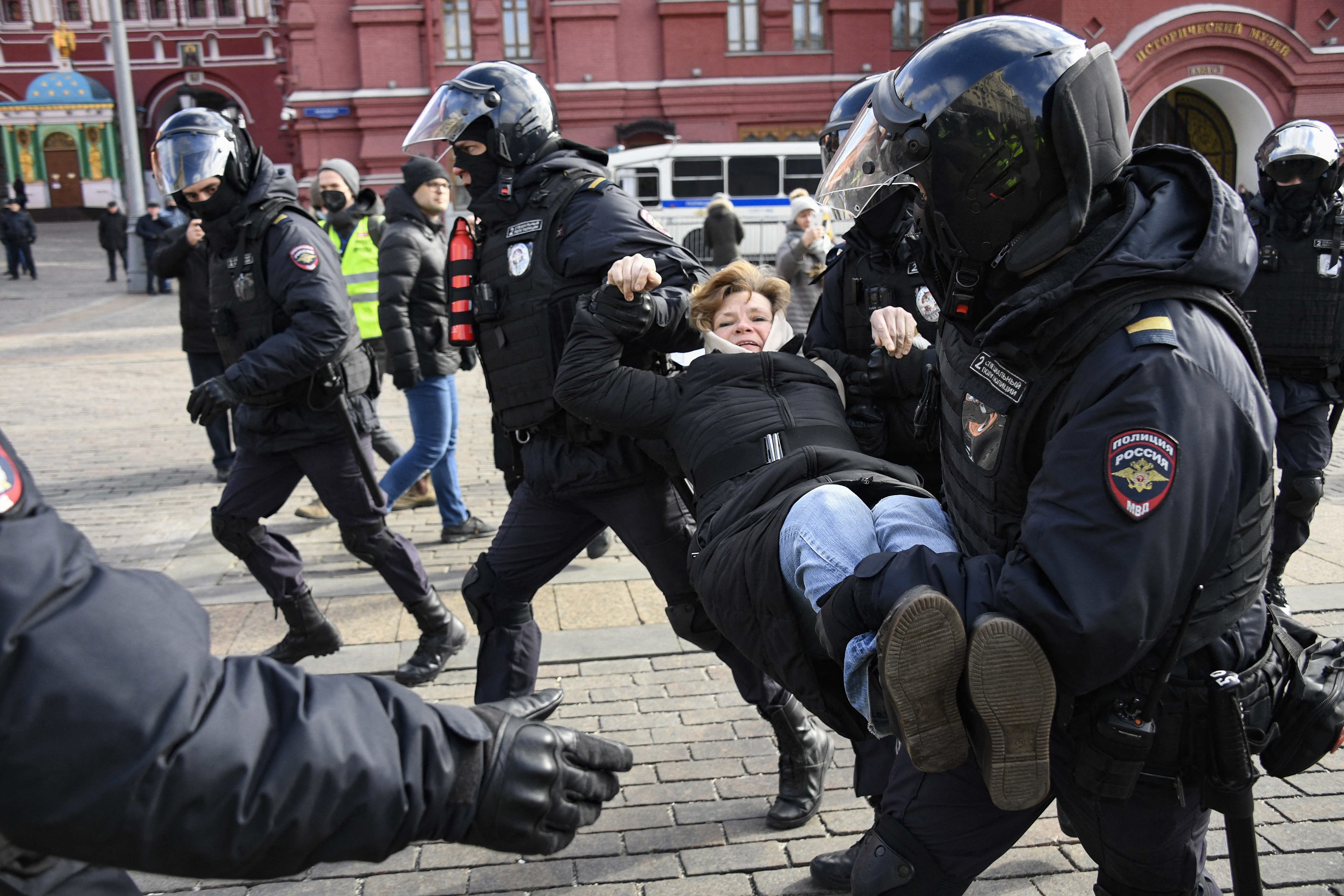 Police officers detain a woman during a protest against Russian military action in Ukraine.