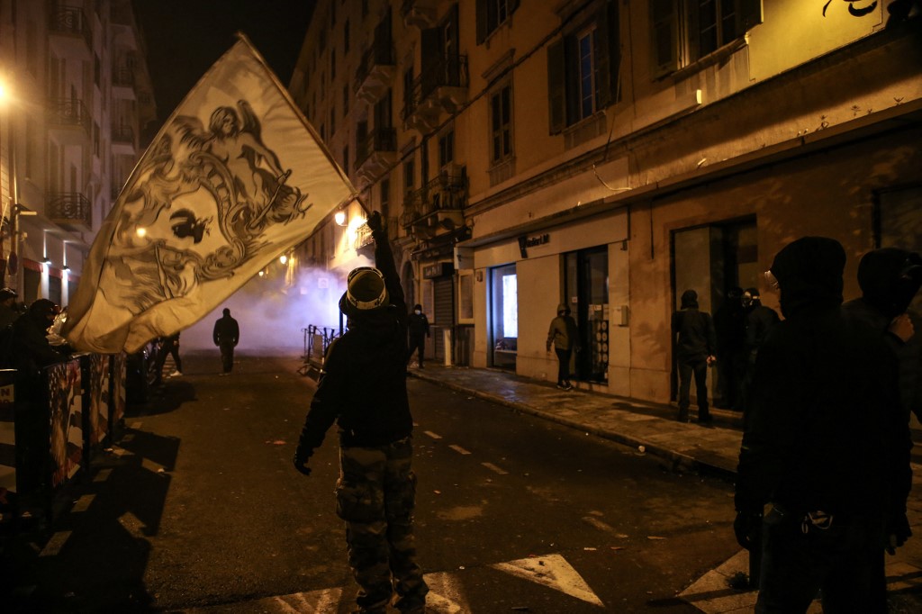 A protester waves a Corsican flag during clashes with police