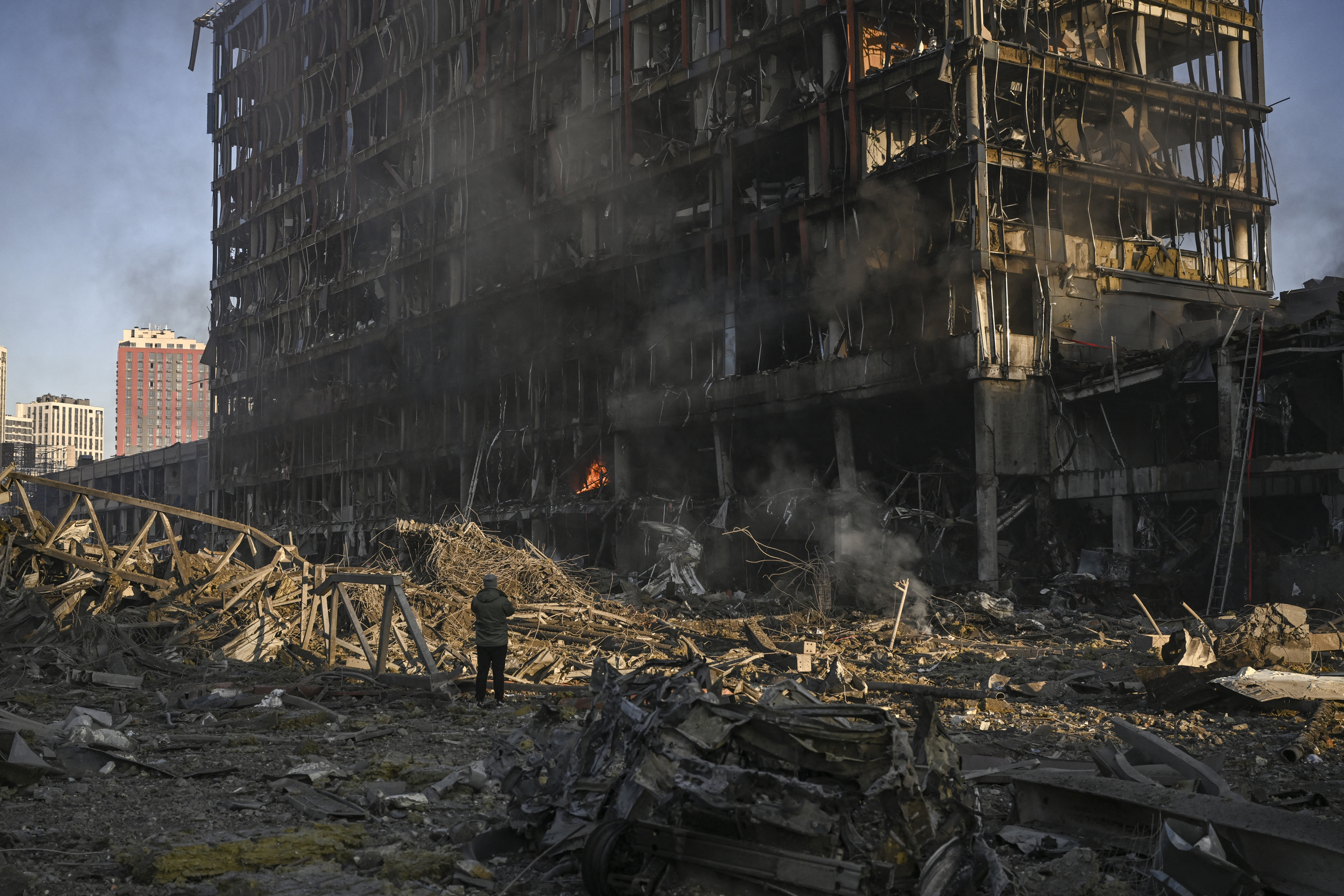 A man stand looking at the burning and destroyed Retroville shopping mall