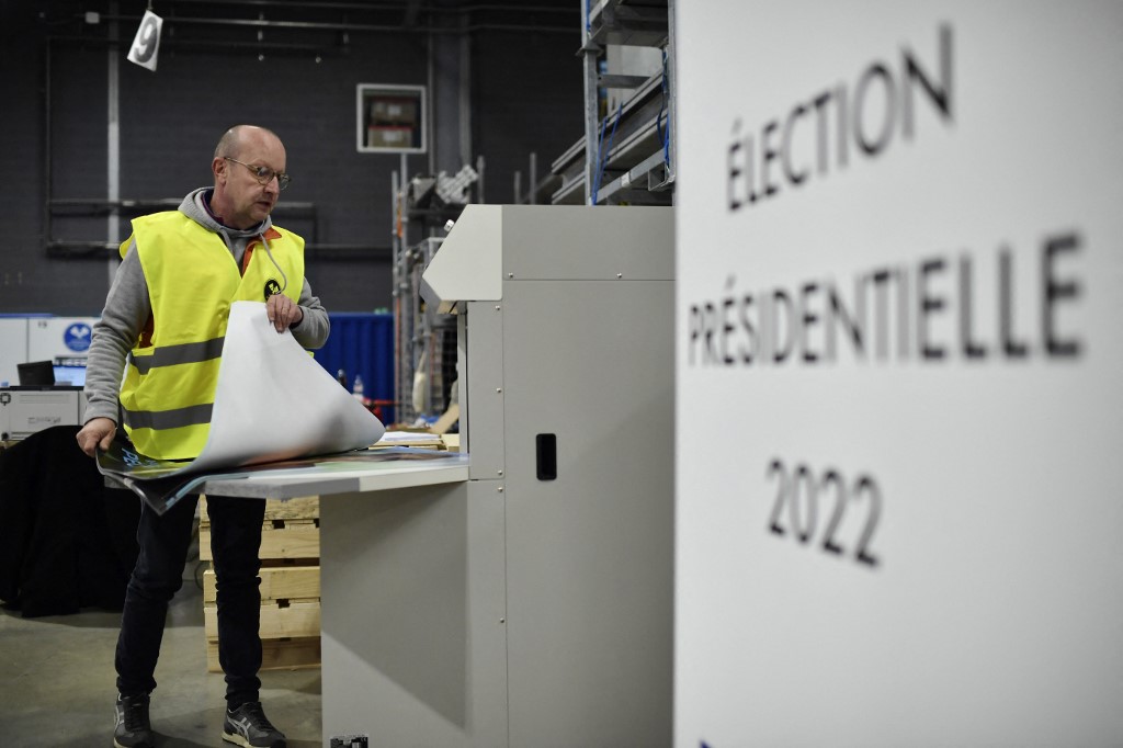 An employee prepares official campaign posters of French presidential candidates