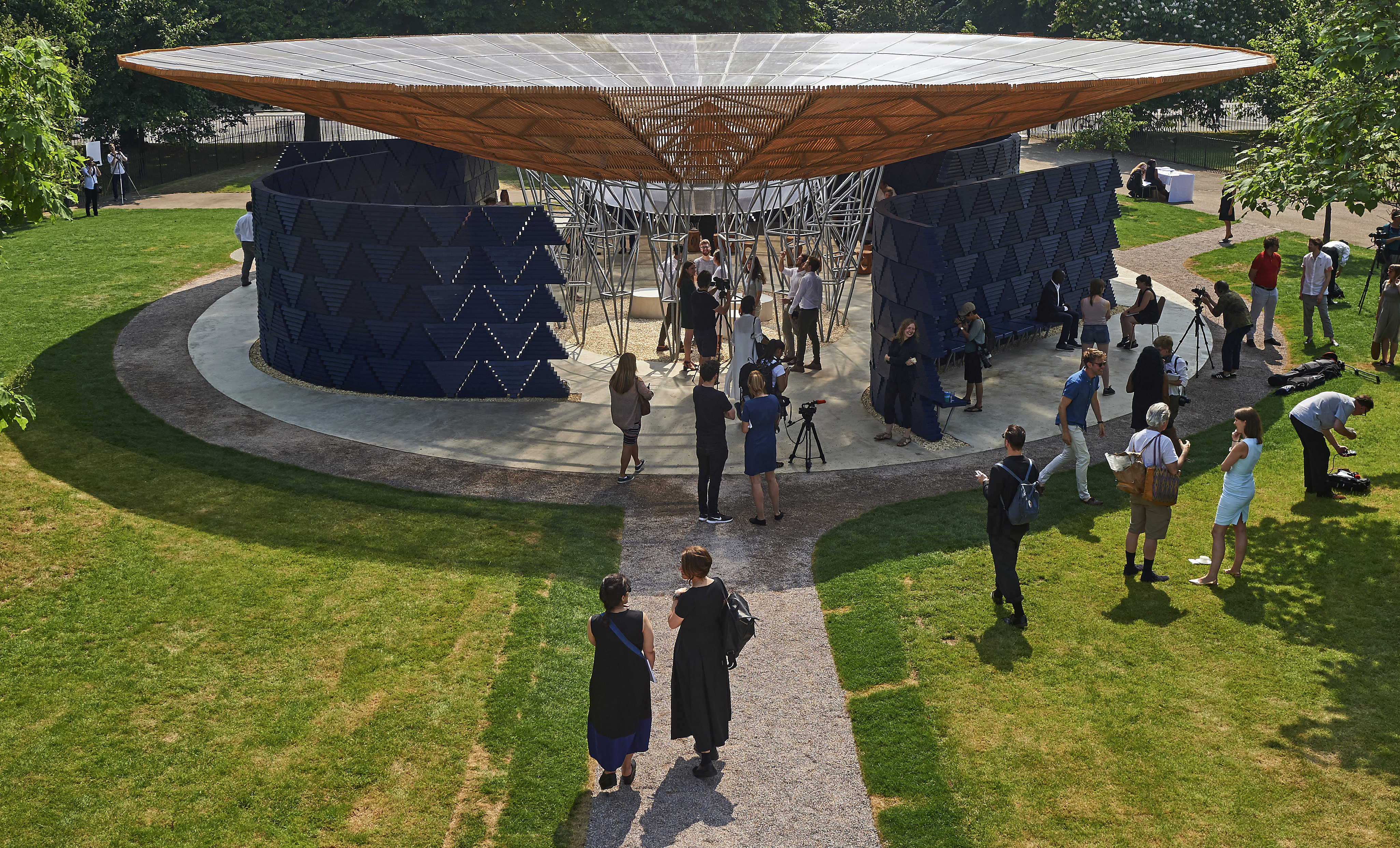 People mill around on the grass near the pavilion designed by Diebedo Francis Kere at London's Serpentine Gallery in 2017