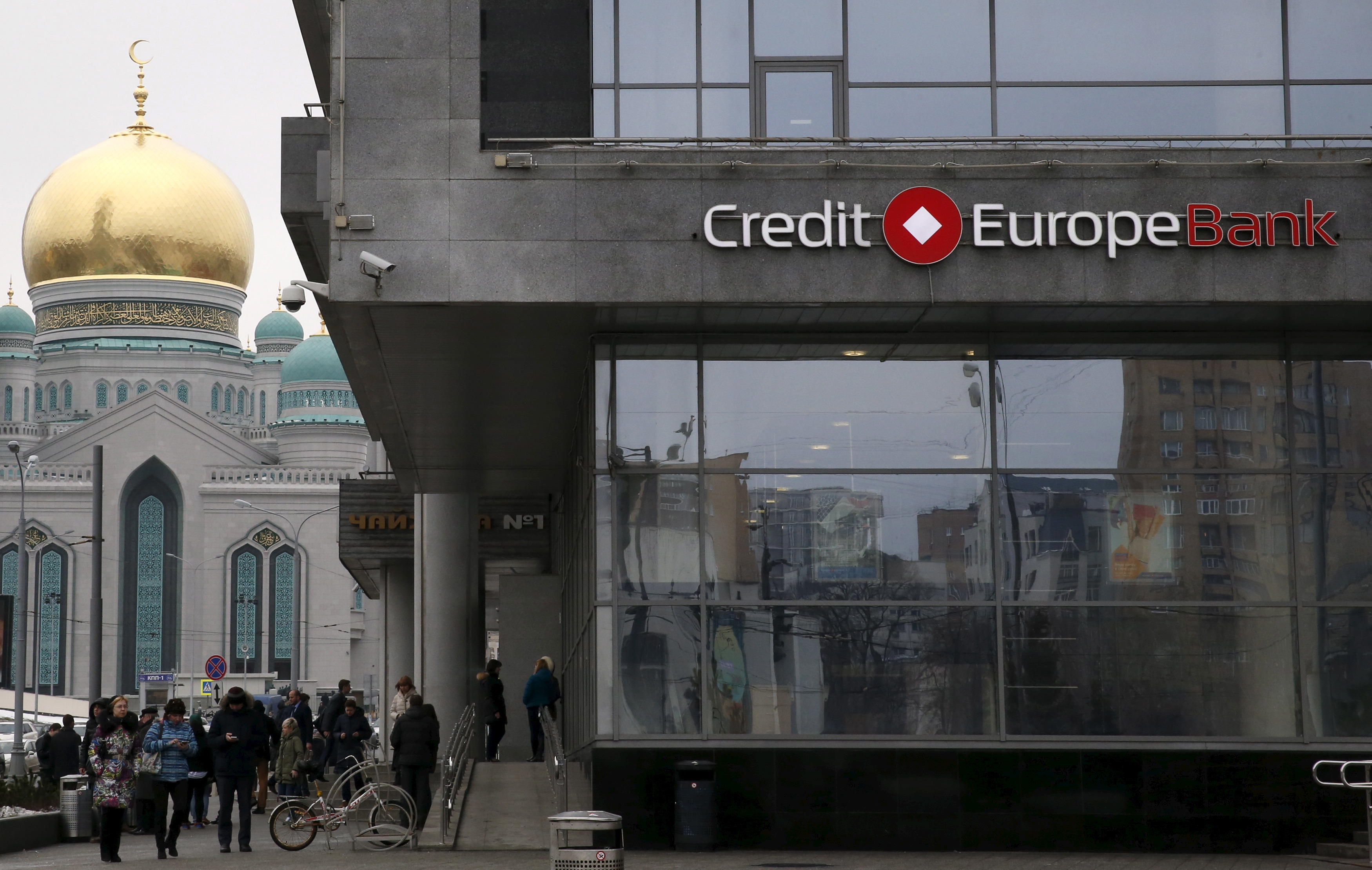 People walk near a branch of the Credit Europe Bank in Moscow.