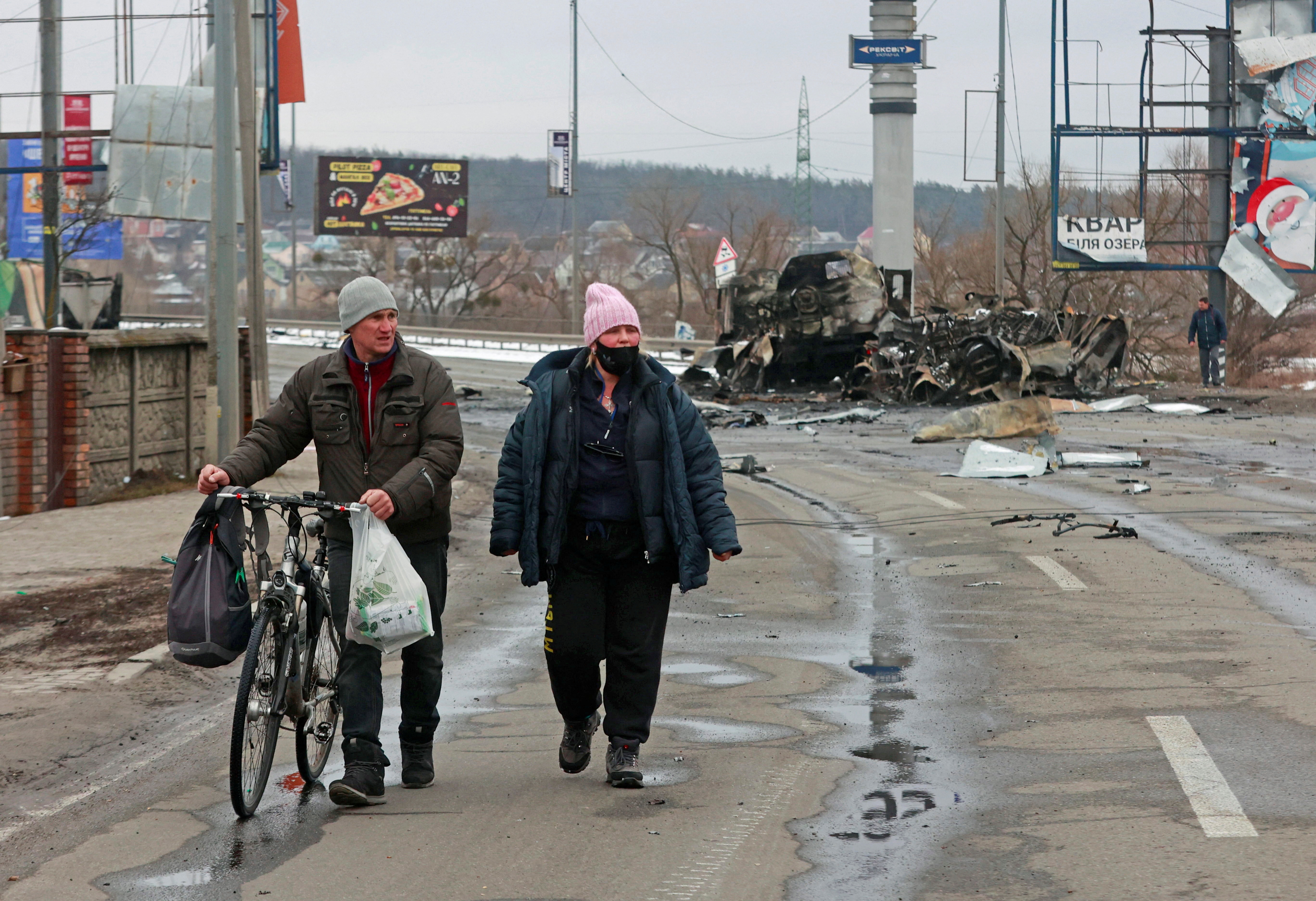 Local residents walk past destroyed military vehicles, as Russia's invasion of Ukraine continues, in the town of Bucha in the Kyiv region, Ukraine March 1,