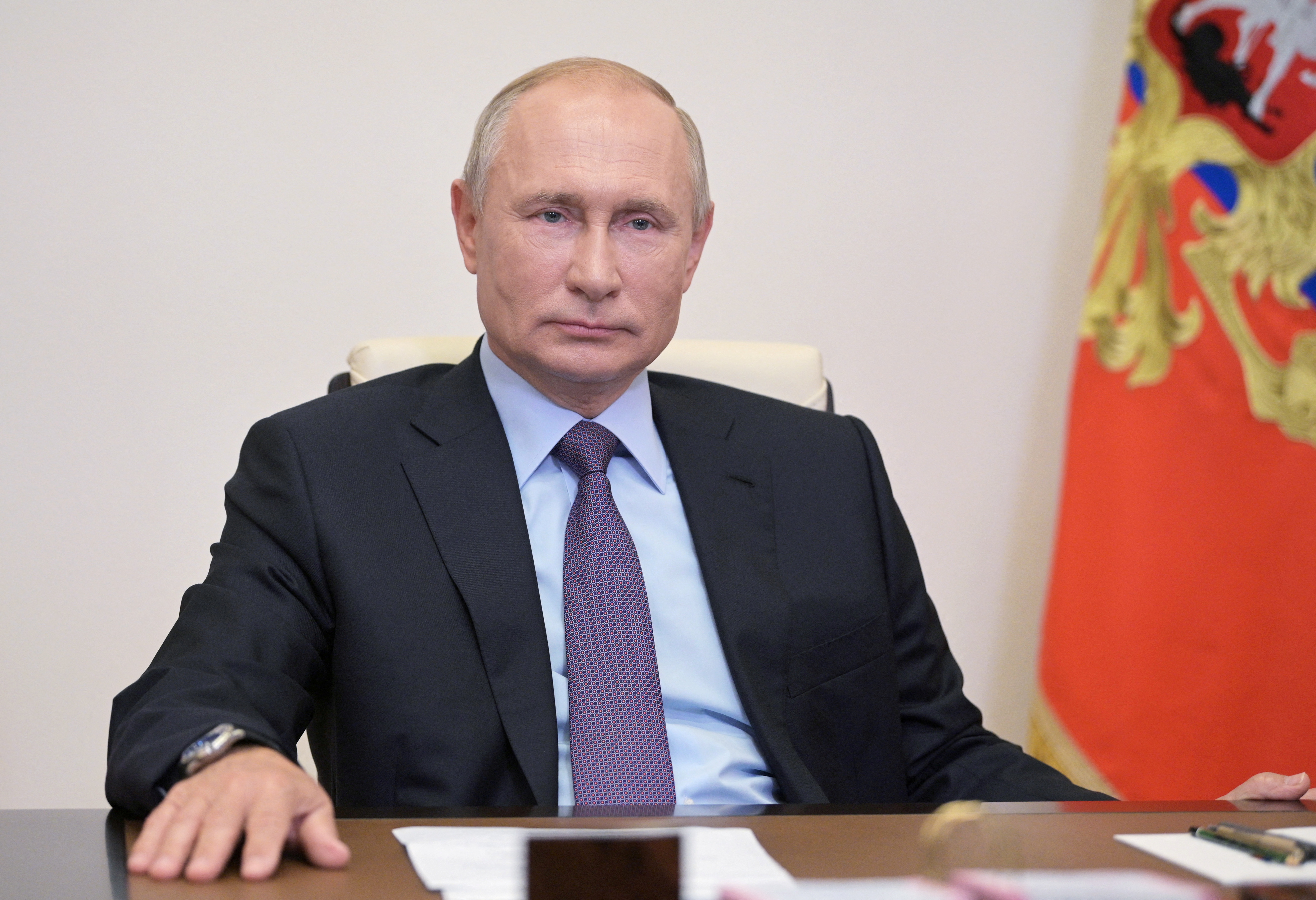 Russian President Vladimir Putin is seen sitting at a table