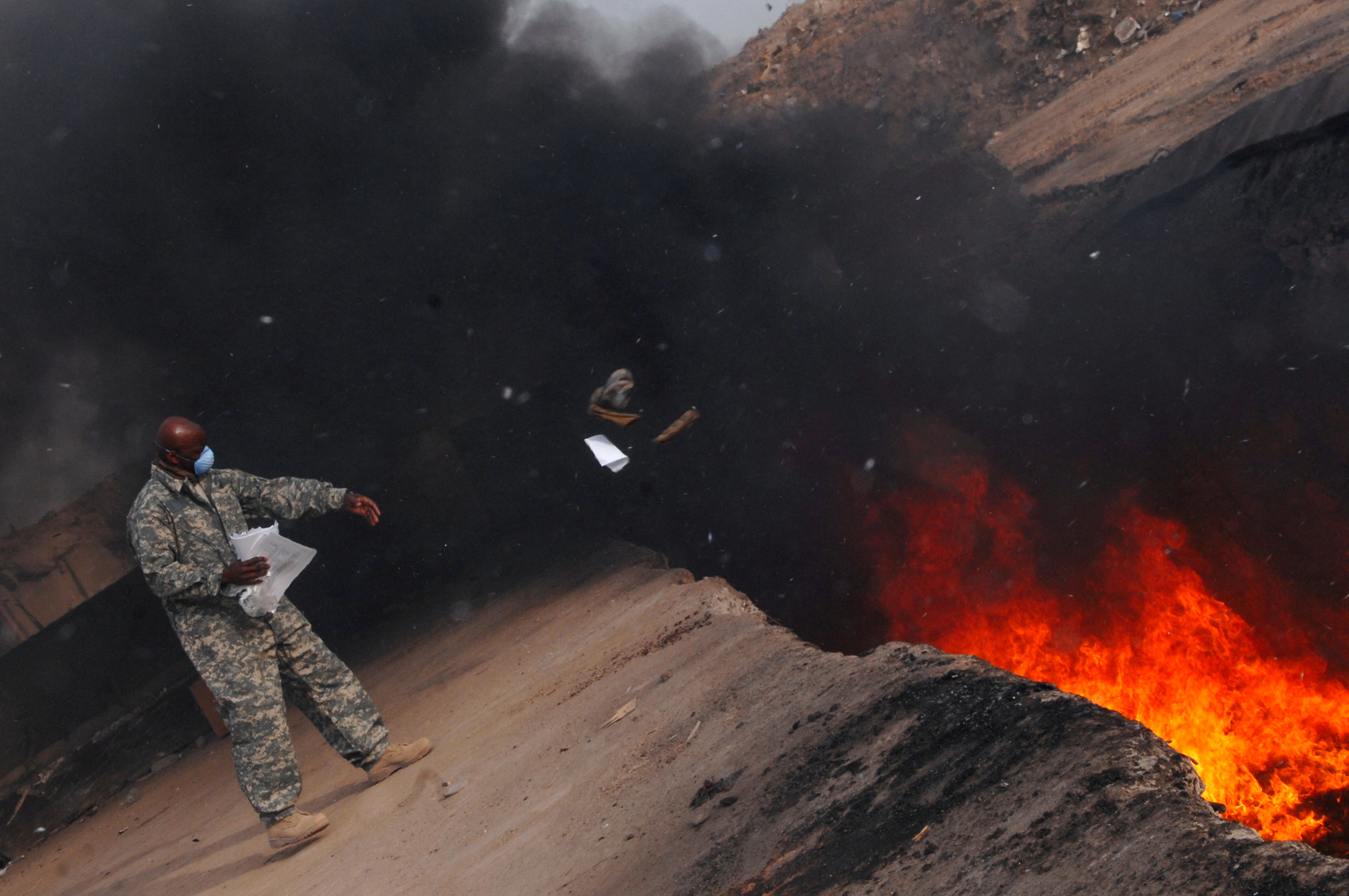 Master Sgt. Darryl Sterling, 332nd Expeditionary Logistics Readiness Squadron equipment manager, tosses unserviceable uniform items into a burn pit at Balad Air Base in Balad, Iraq March 10, 2008. 