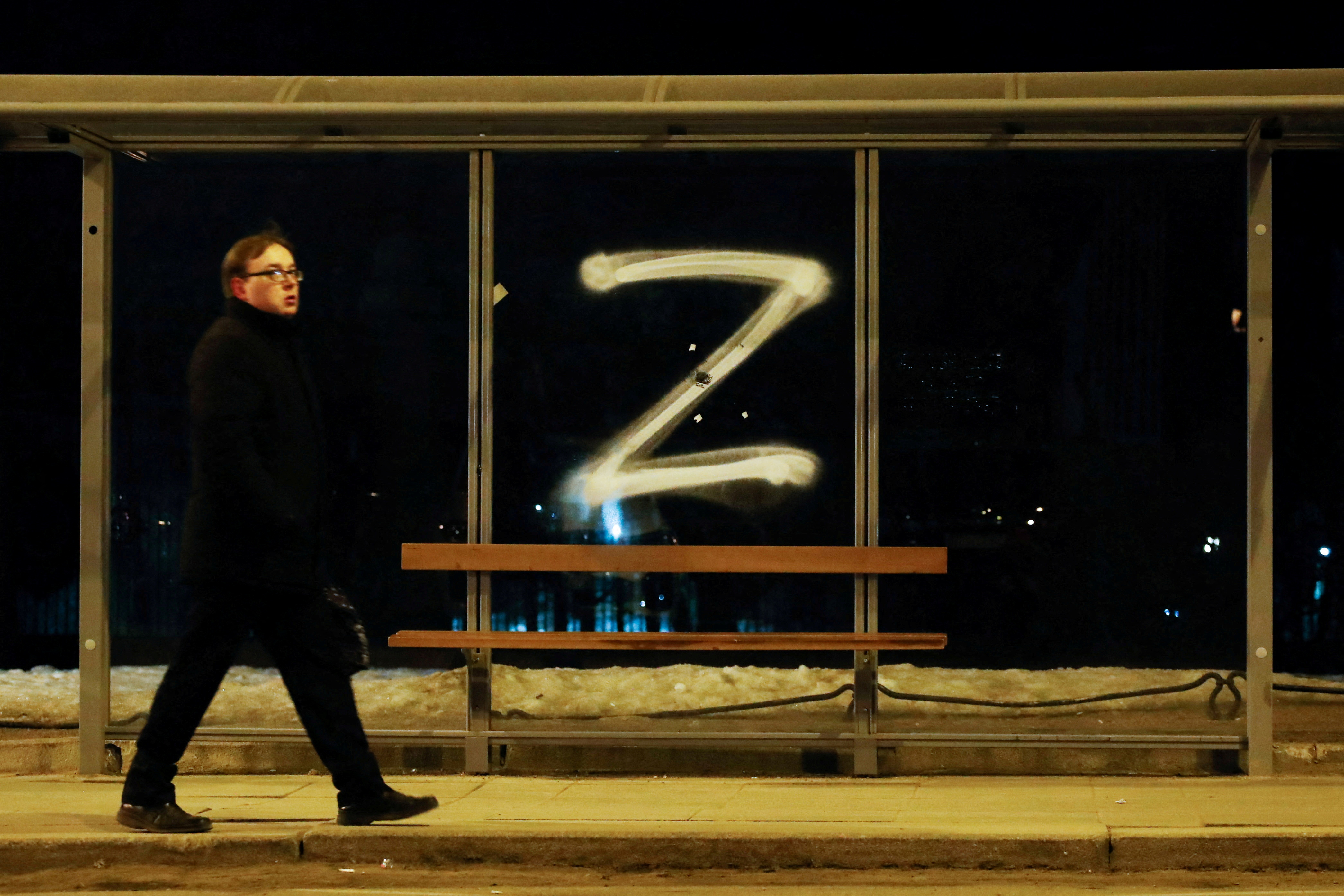 A man walks past the symbol "Z" painted on a bus stop in support of the Russian armed forces
