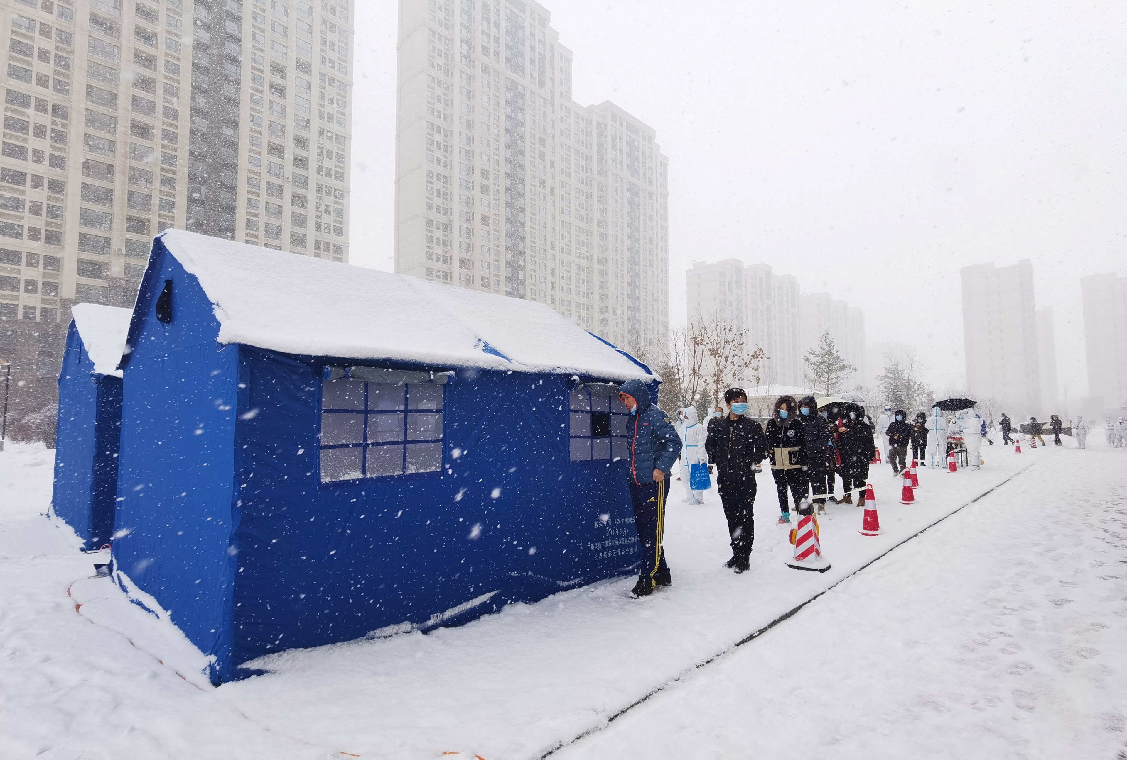 Residents line up at a makeshift nucleic acid testing site amid snowfall
