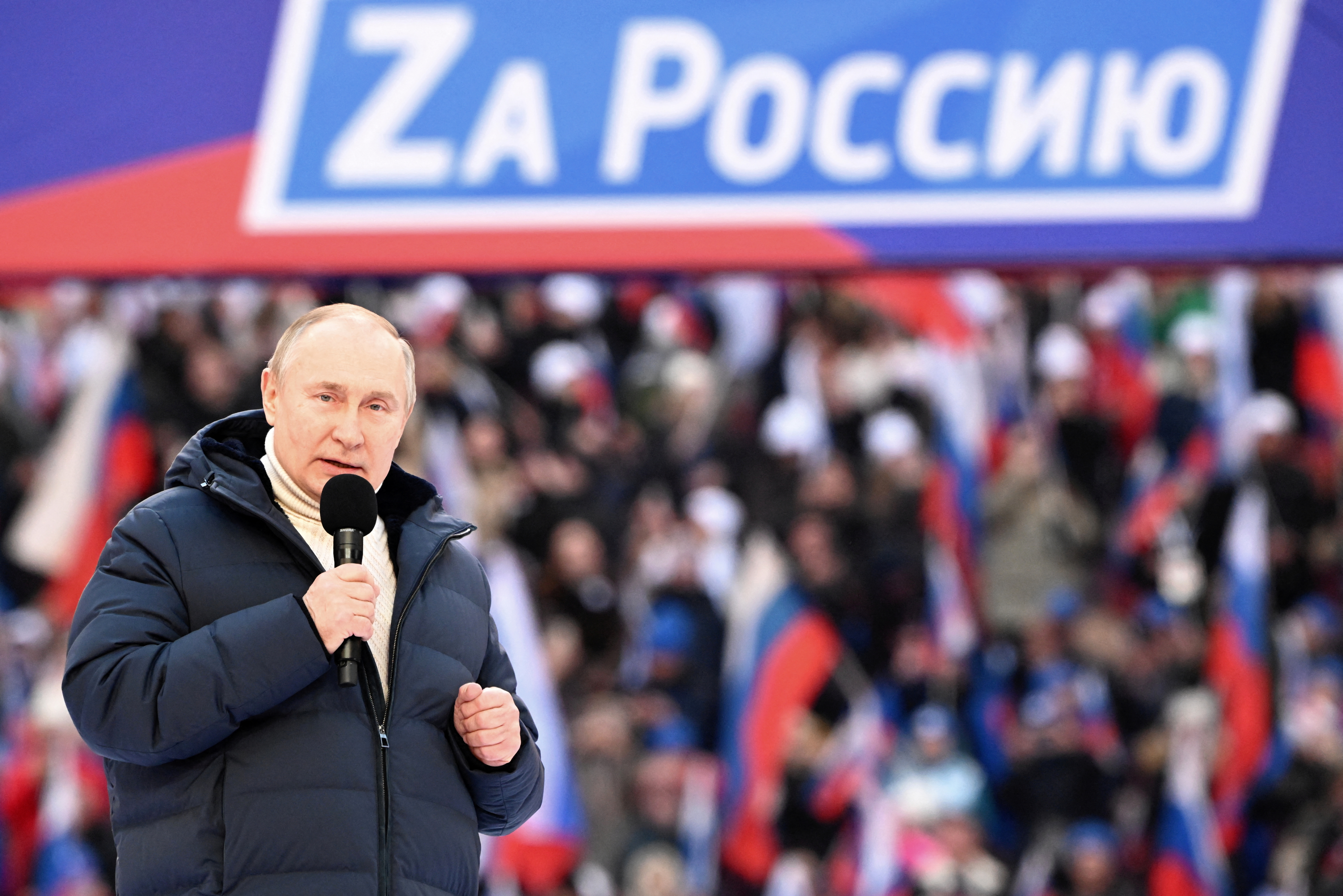 Russian President Vladimir Putin delivers a speech during a concert marking the eighth anniversary of Russia's annexation of Crimea at Luzhniki Stadium in Moscow. The banner reads: "For Russia".