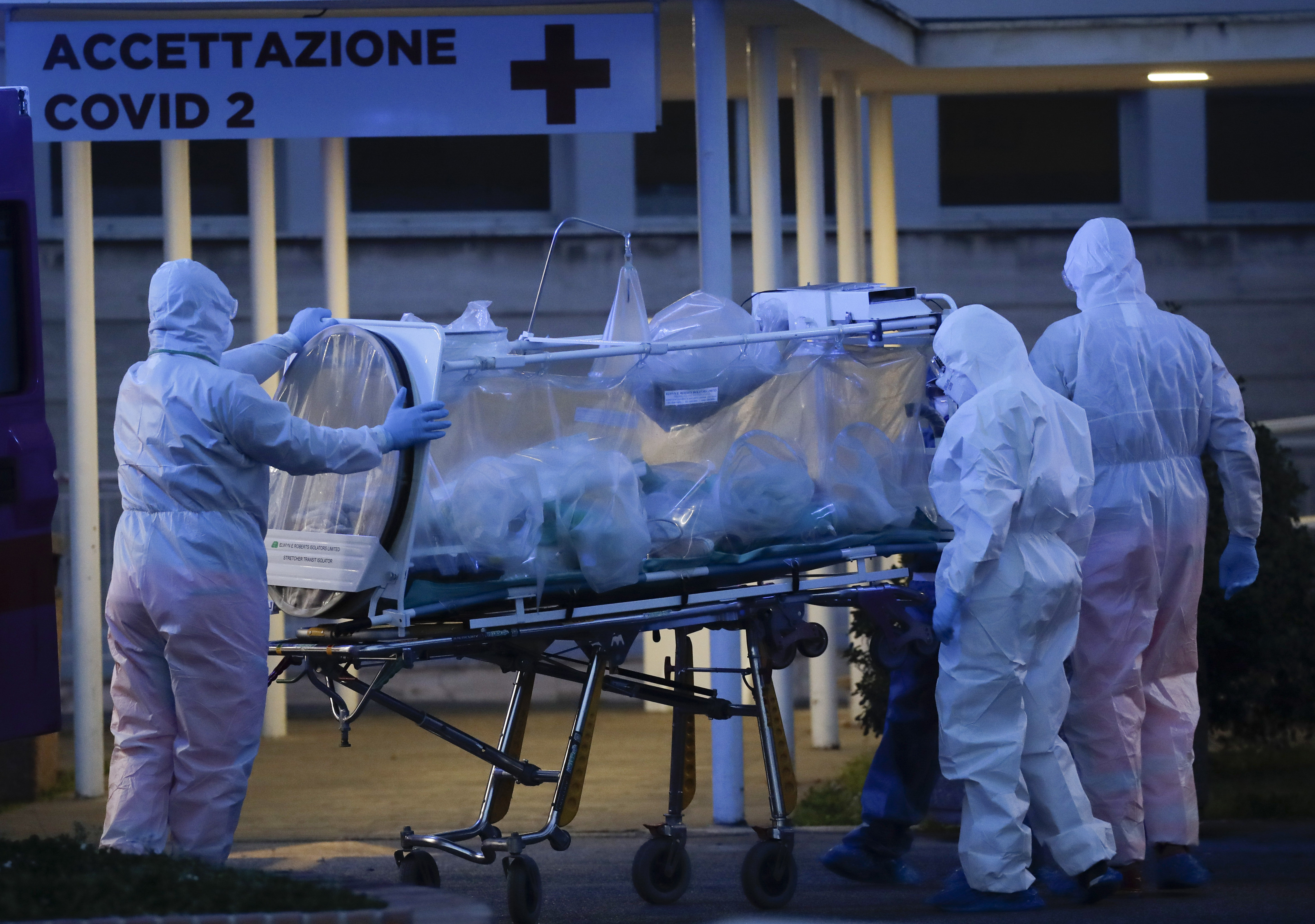 A patient in a biocontainment unit is carried on a stretcher at the Columbus Covid 2 Hospital in Rome, Monday, March 16, 2020. The new Columbus Covid 2 Hospital, an area fully dedicated to the COVID-19 cases at the Gemelli university polyclinic, opened today with 21 new ICU units and 32 new beds, in order to support the regional health authorities in trying to contain the pandemic. Sign at top in Italian reads "Admission COVID 19". For most people, the new coronavirus causes only mild or moderate symptoms. For some it can cause more severe illness, especially in older adults and people with existing health problems.