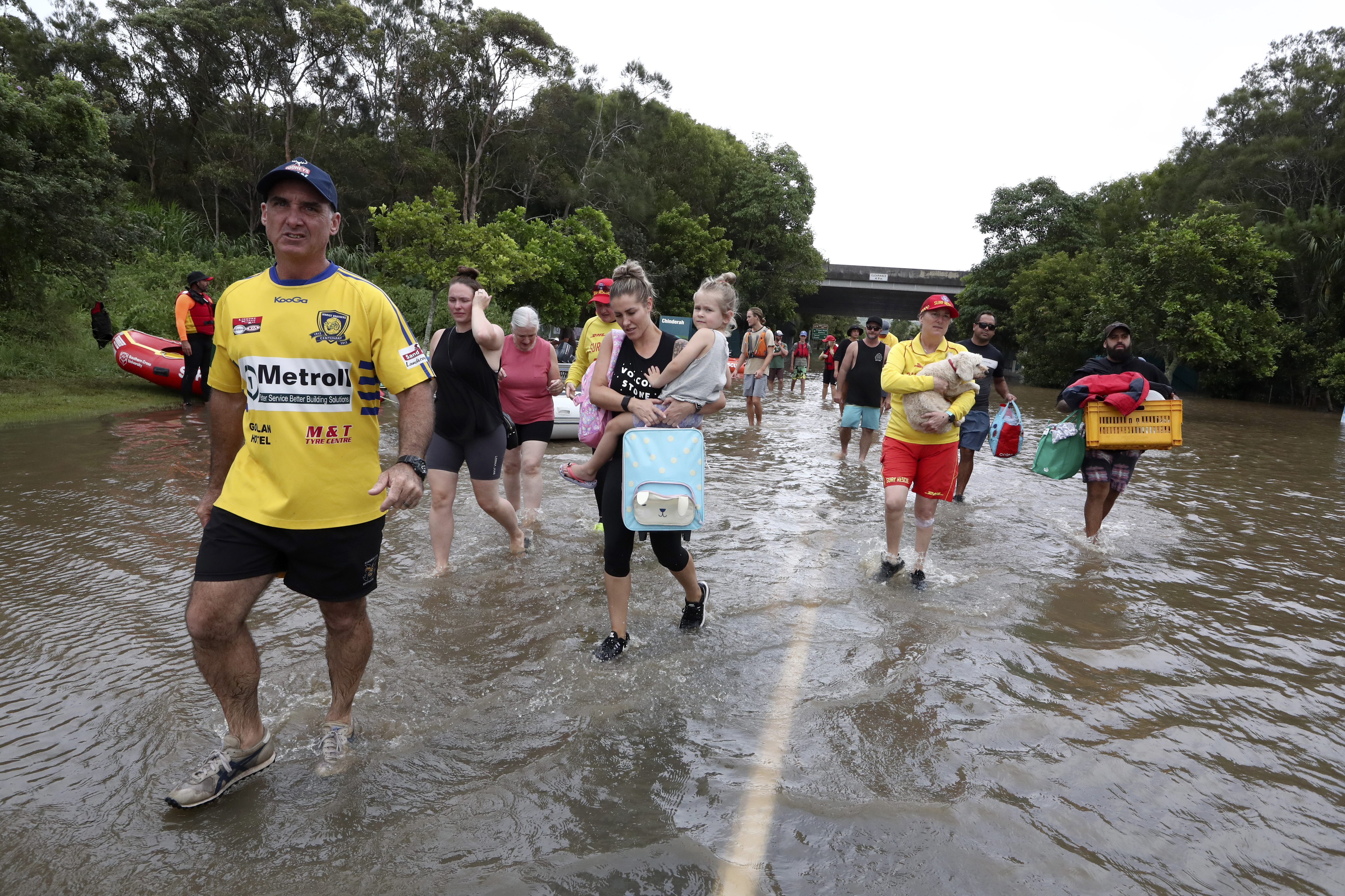 People wade through flood water as they relocate in Chinderah