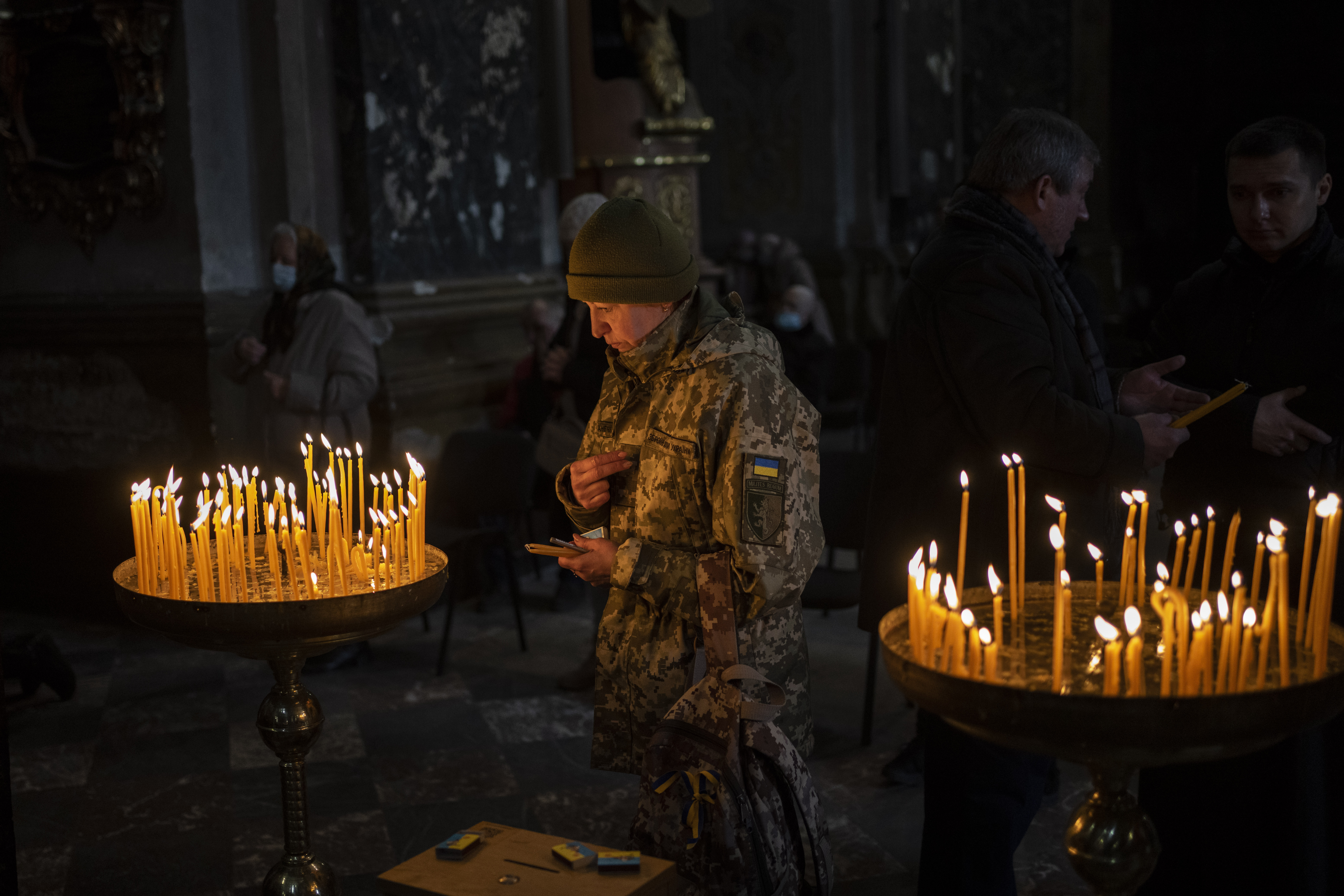 A Ukrainian woman dressed in military attire prays inside the Saints Peter and Paul Garrison Church in Lviv