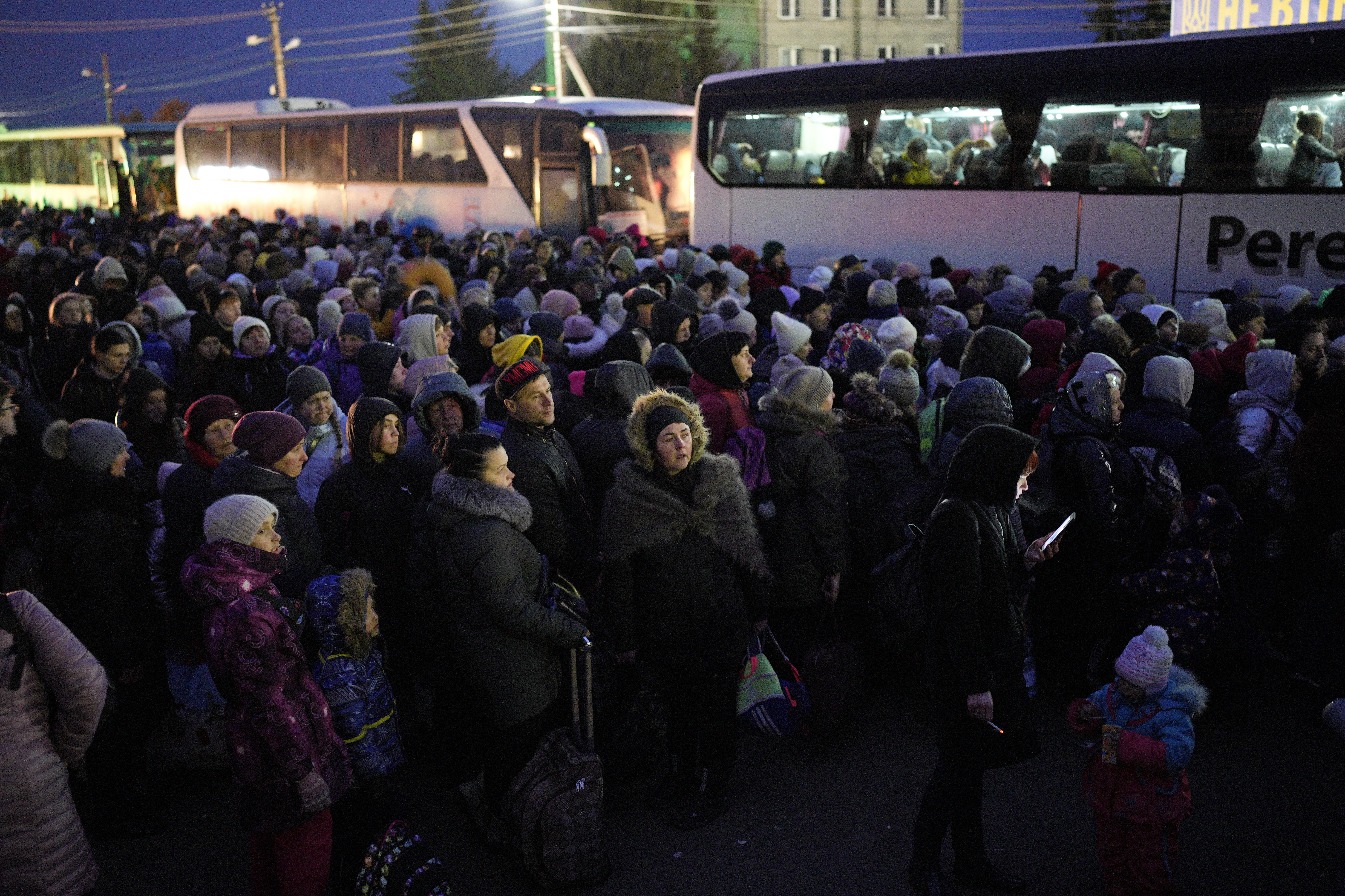 Refugees fleeing the war in Ukraine form a line as they approach the border with Poland in Shehyni