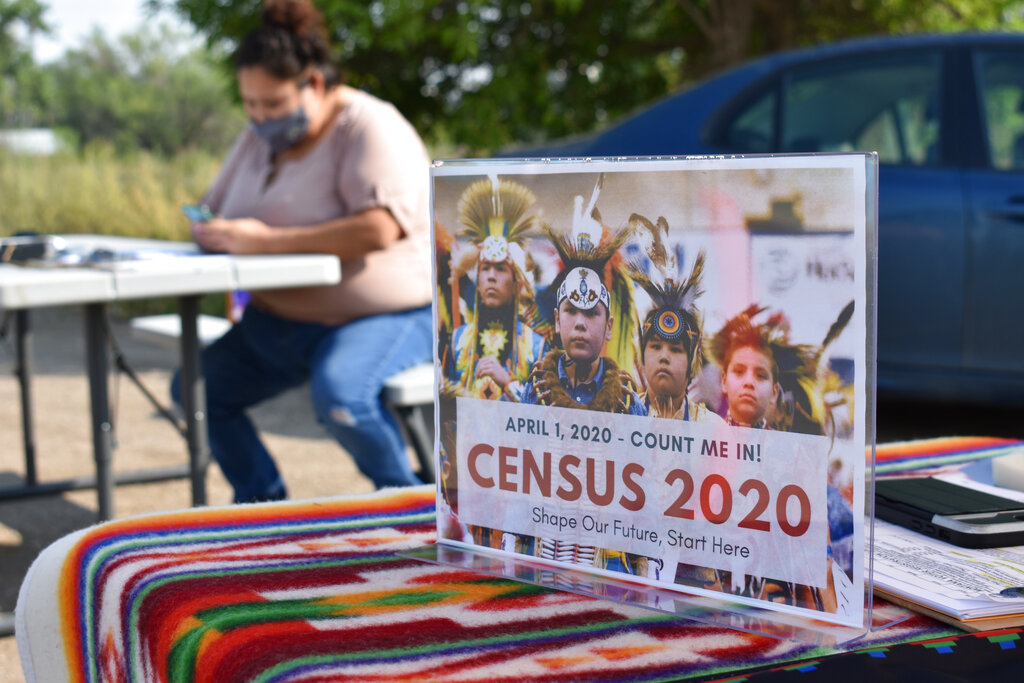 A sign promoting Native American participation in the U.S. census is displayed as Selena Rides Horse enters information into her phone on behalf of a member of the Crow Indian Tribe in Lodge Grass, Montana.