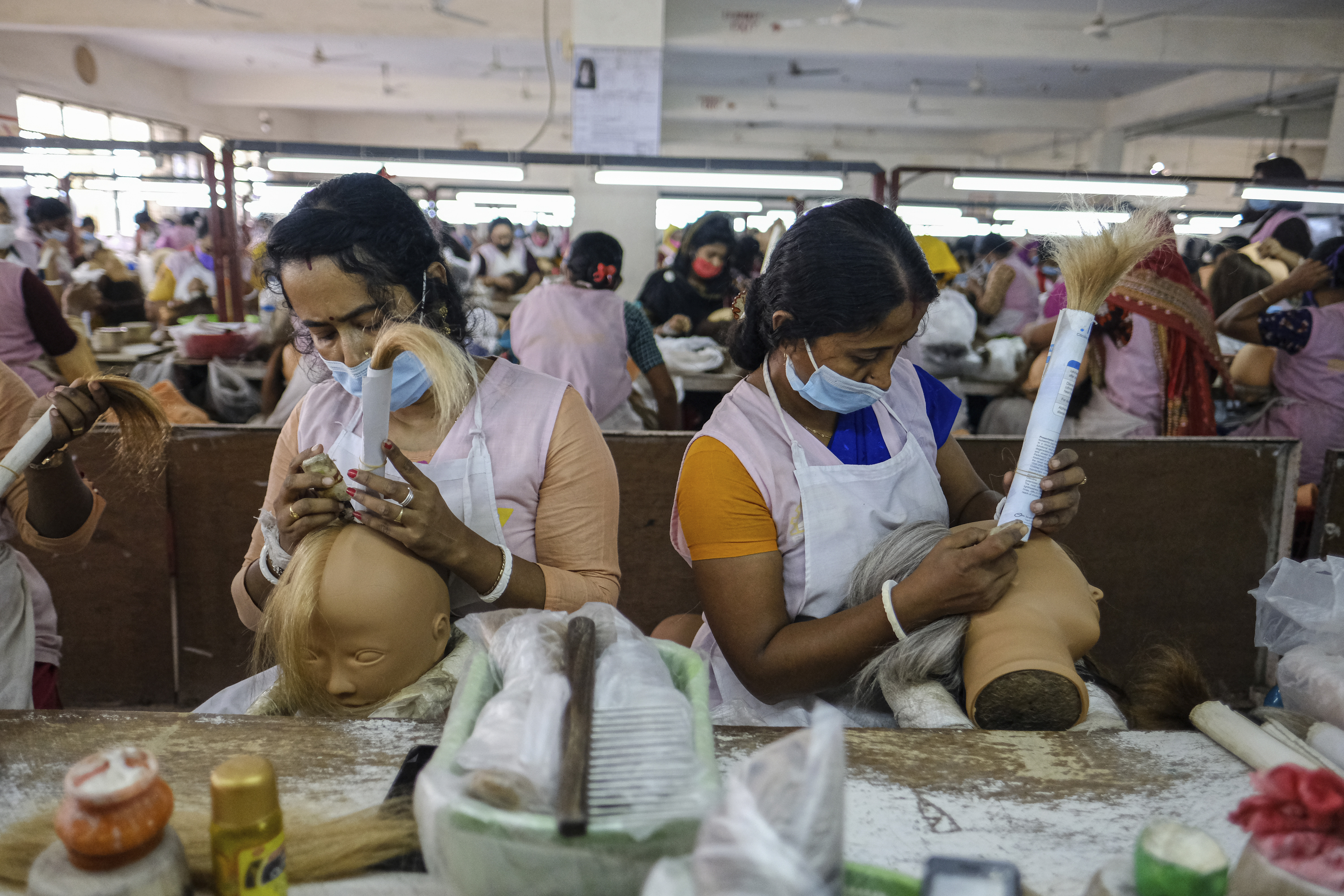 Workers set hair on mannequins at a factory inside an export processing zone in Mongla