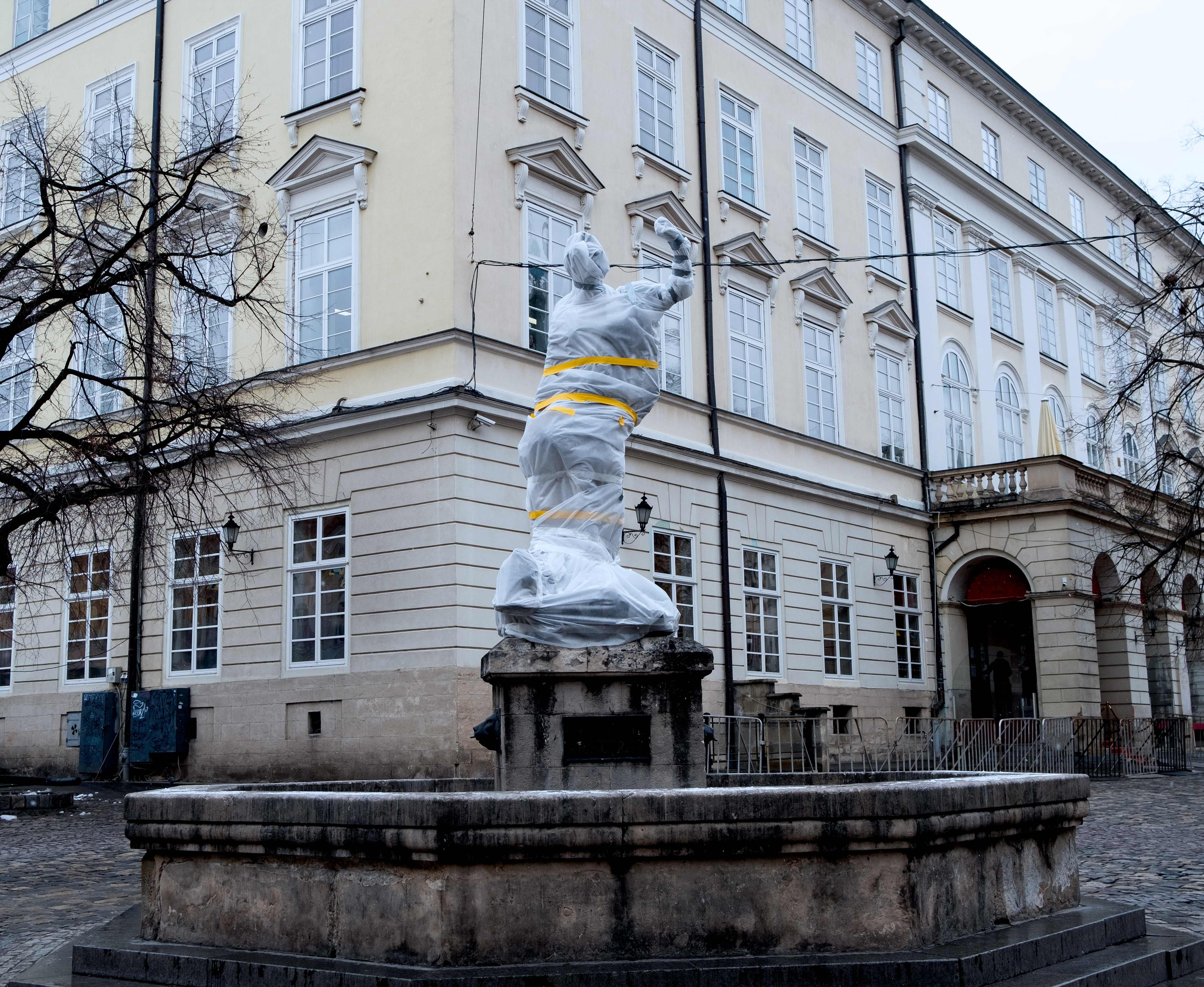 A photo of a statue covered in plastic wrap and tape in a town in Lviv.