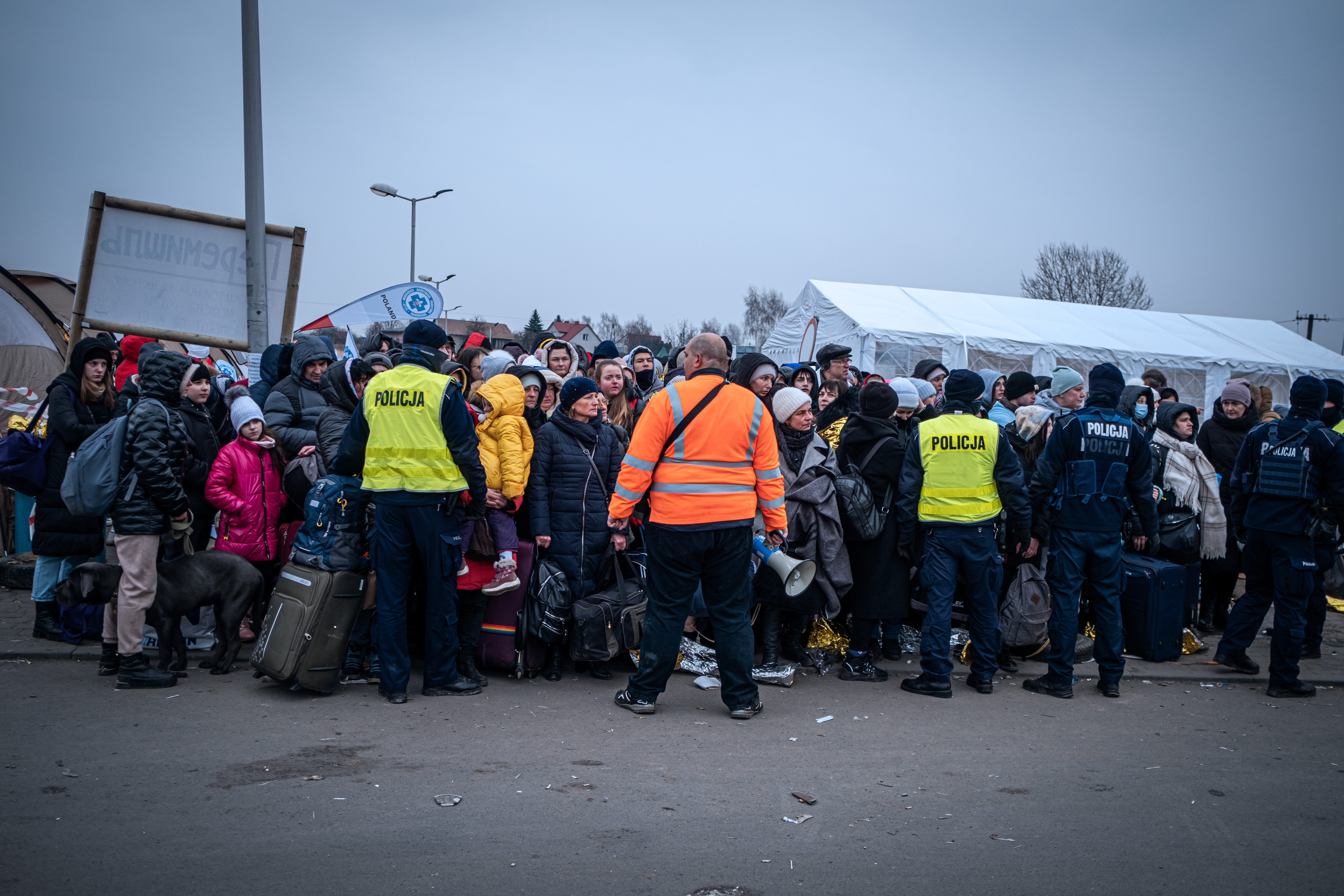 A photo of a crowd of people and four policemen holding them back.