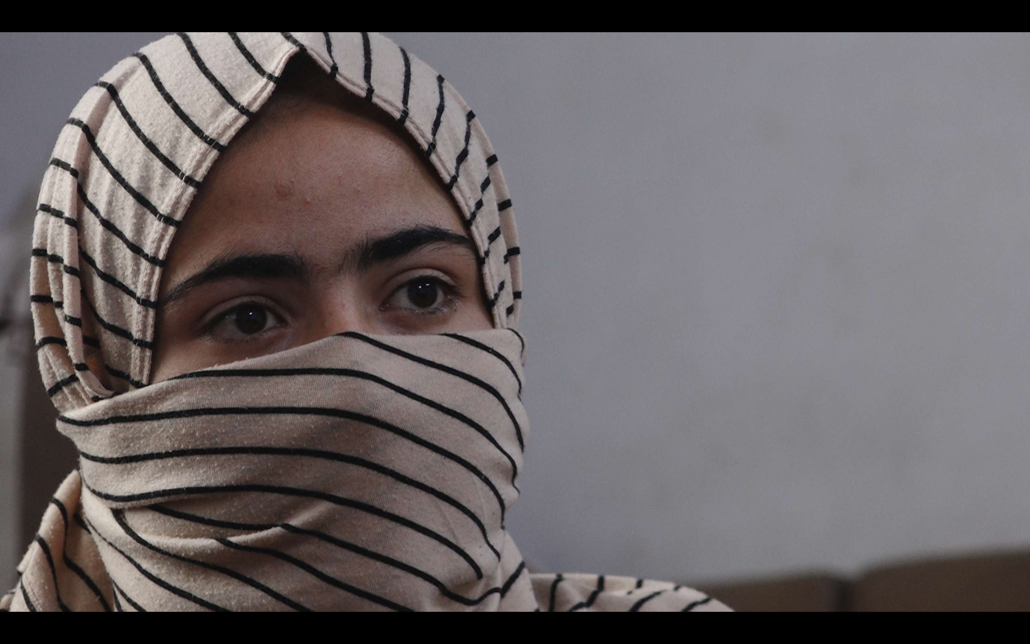 A woman is seen wearing a striped headscarf