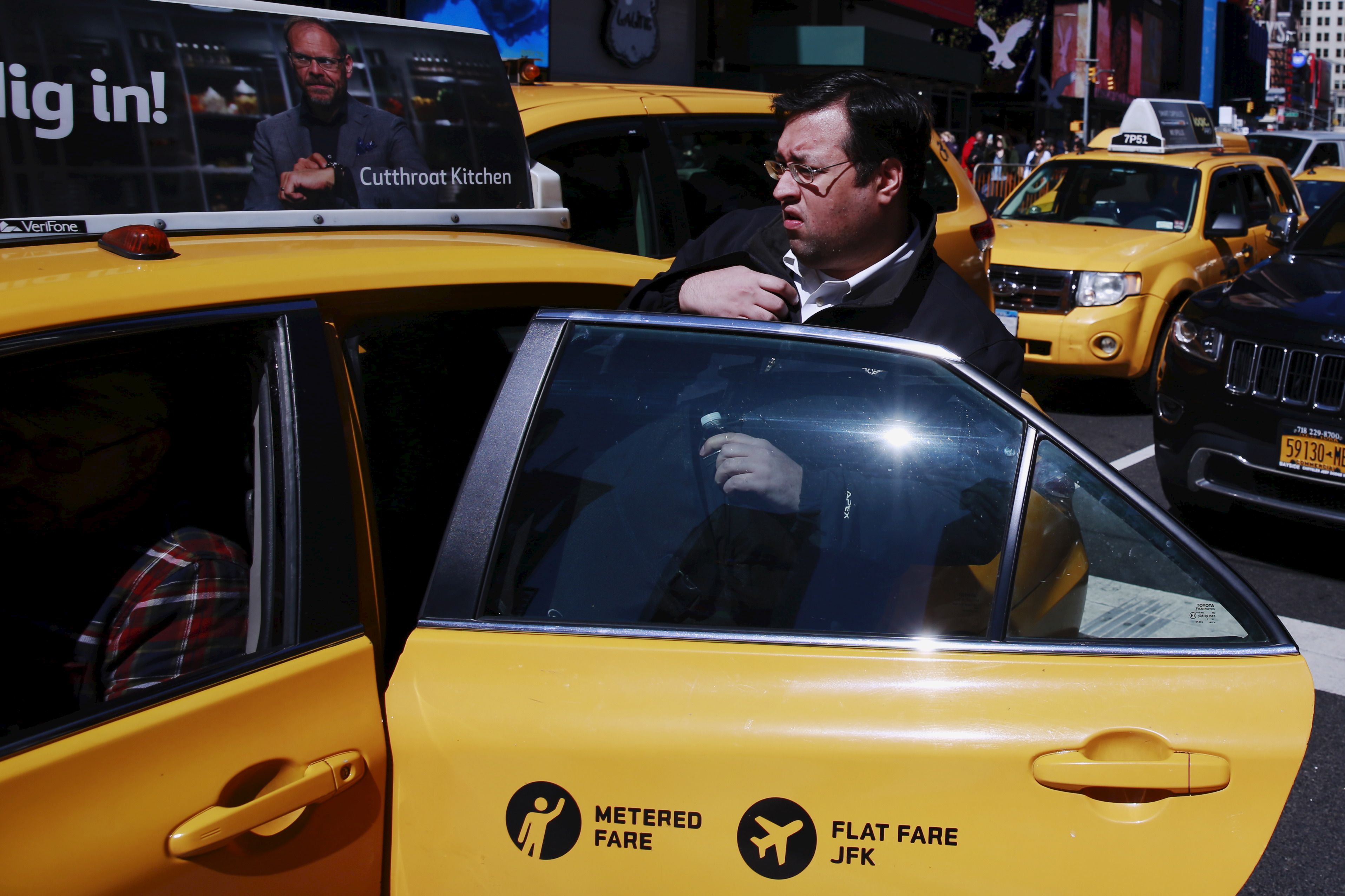 A man enters a New York City taxi cab as it drives through Times Square in New York