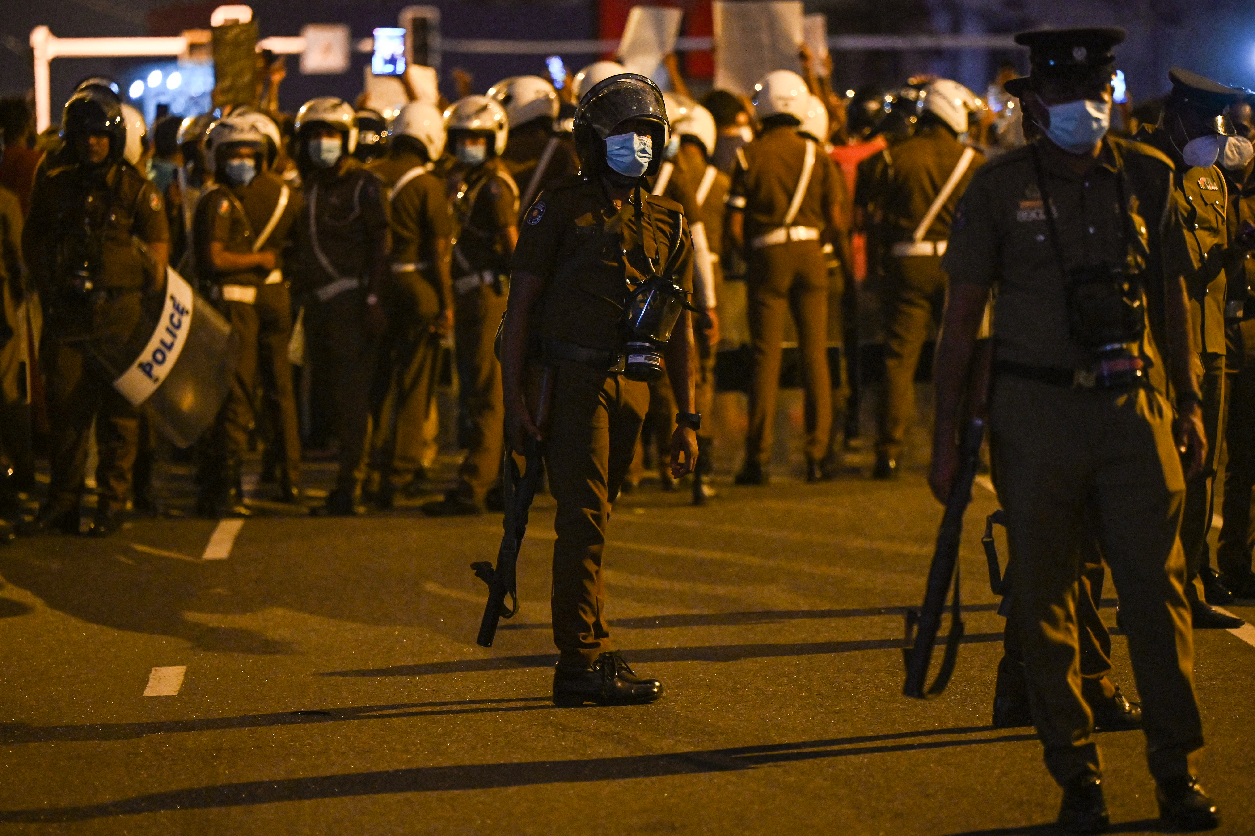 Police stand guard at a spot where protestors take part in a demonstration against the surge in prices and shortage of fuel and other essential commodities in Colombo