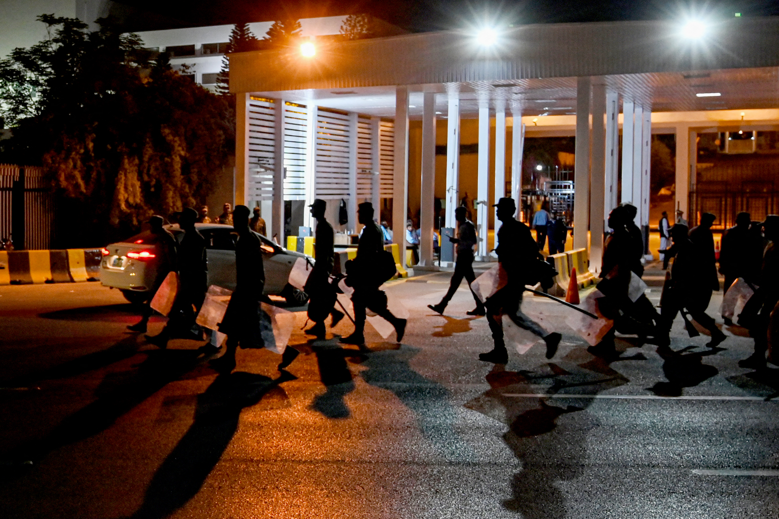 Security personnel walk past in front of the parliament house building in Islamabad