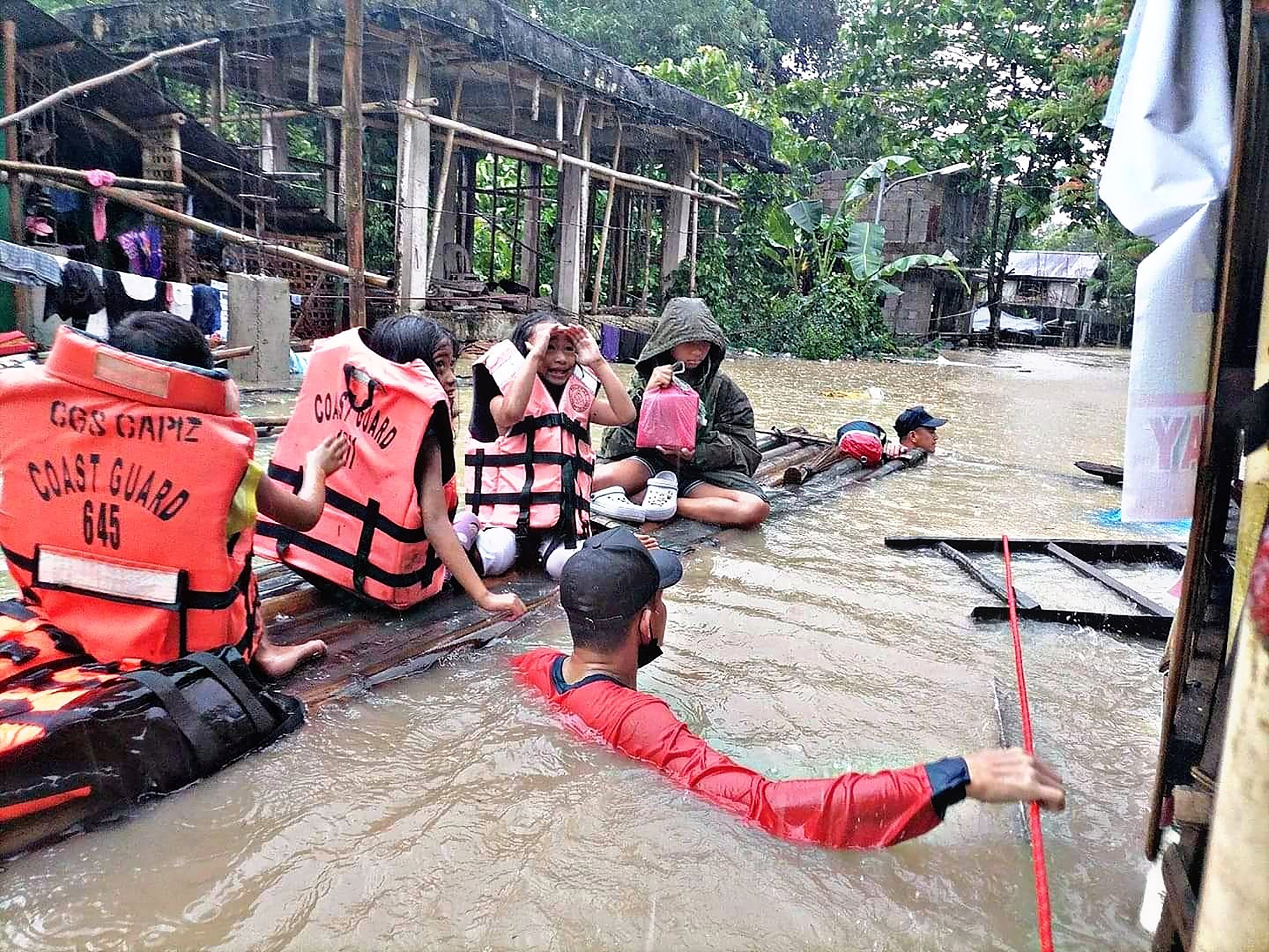 A coast guard officer wades neck deep in water and holds onto a makeshift raft during a search and rescue mission.