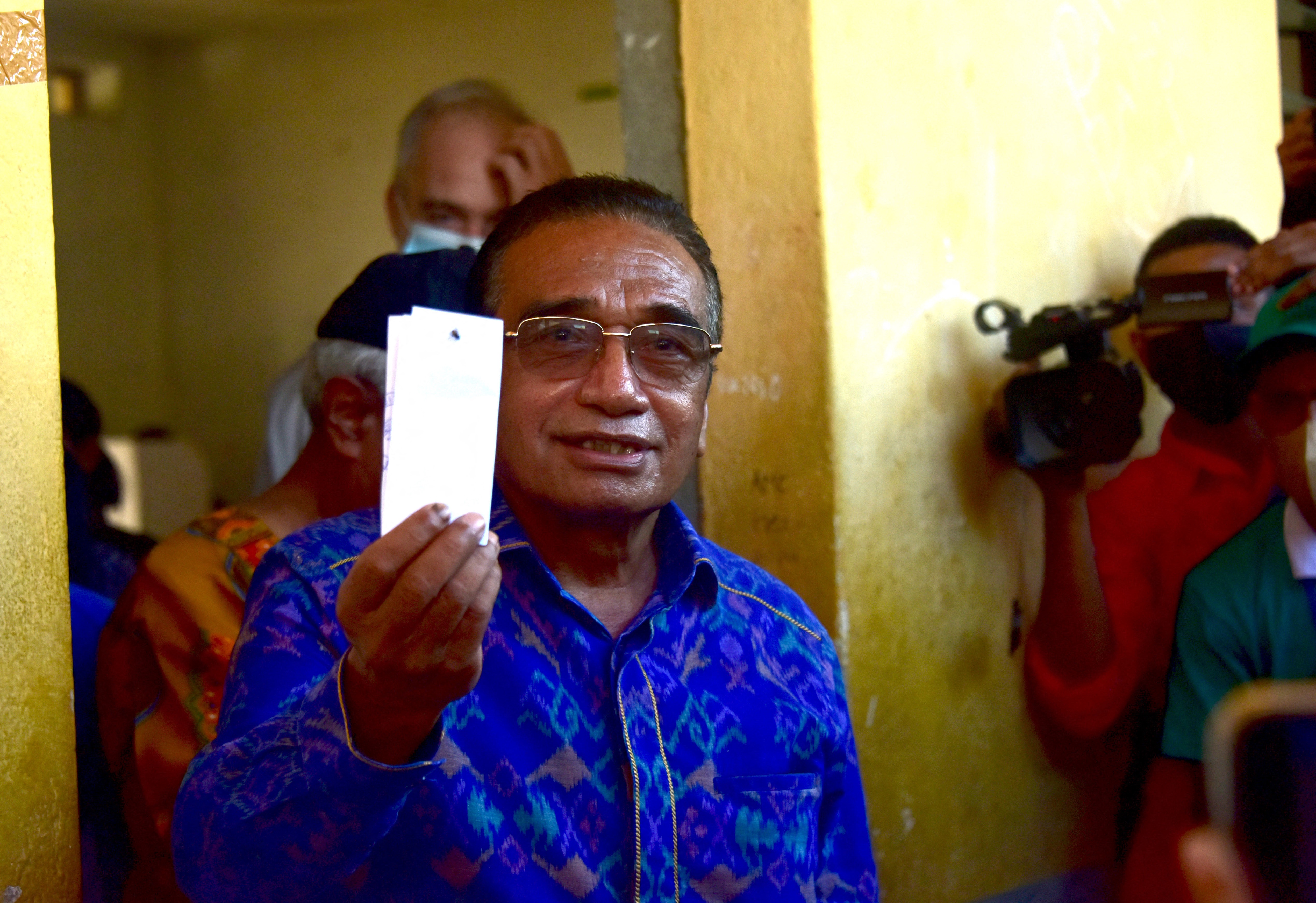 Wearing a royal blue shirt, Francisco Guterres shows his ballot during the second round of presidential elections in Dili