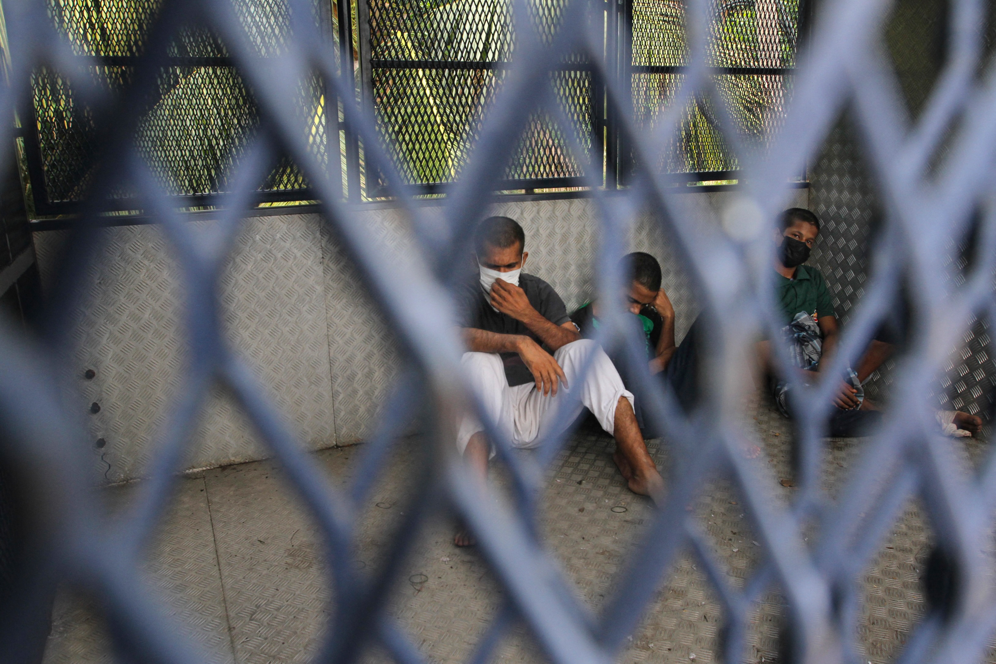 Some Rohingya refugees seen through the wire of a Malaysian immigration truck after being rearrested on Wednesday