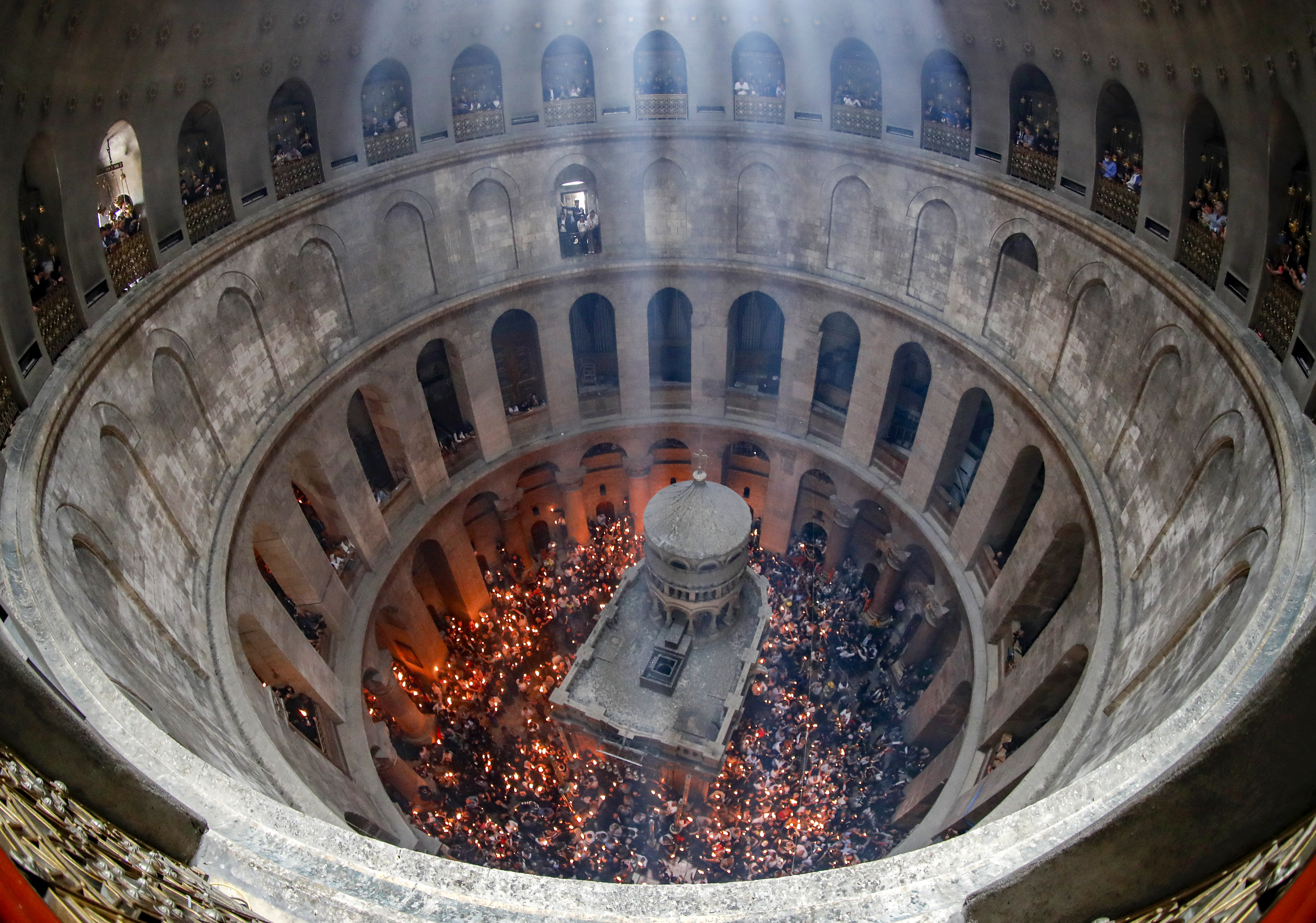 Orthodox Christians gather with lit candles around the Edicule