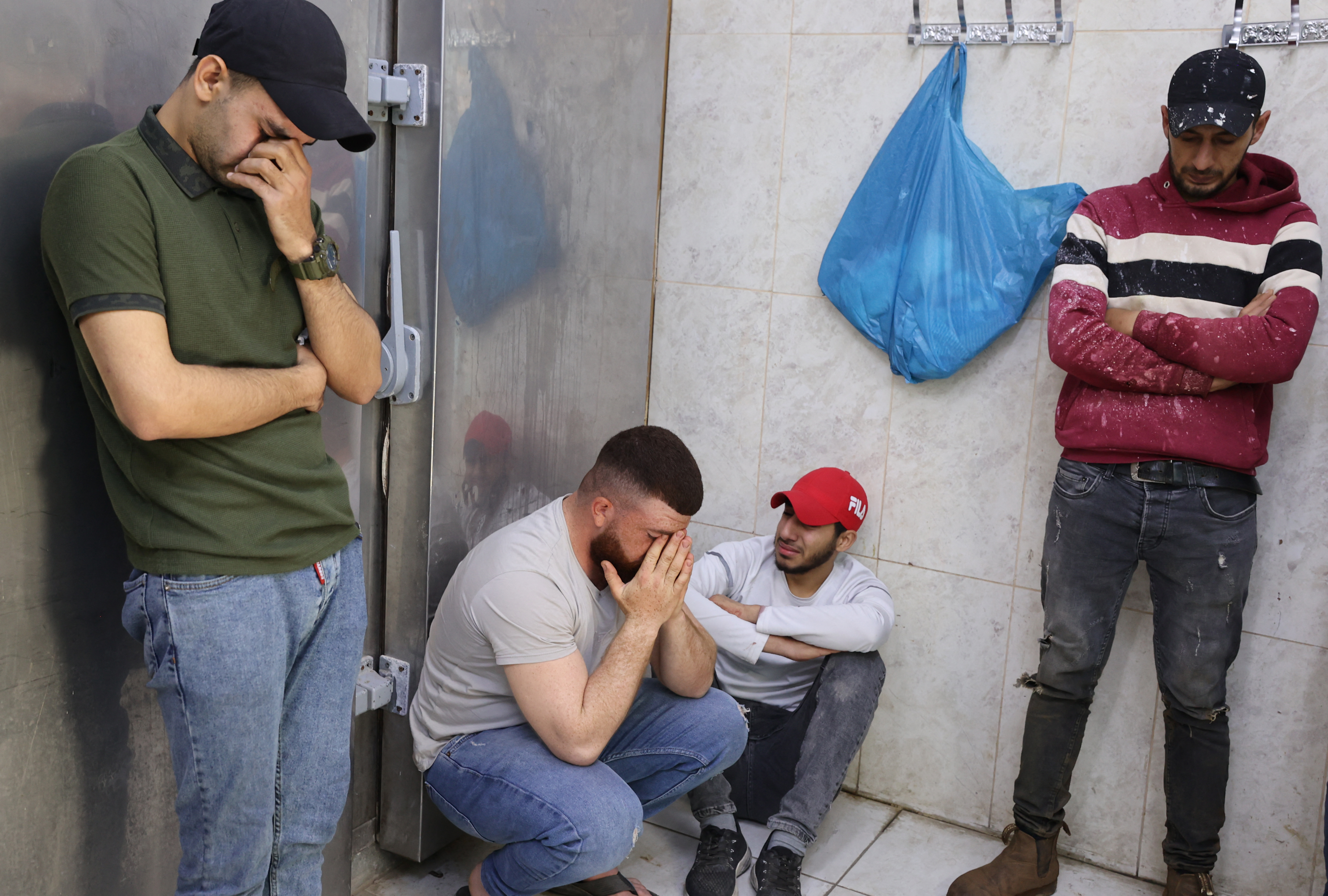 Palestinian men mourn at the morgue of a hospital in Jenin in the occupied West Bank on April 27, 2022. - Israeli forces killed a Palestinian man and wounded three others in West Bank clashes early Wednesday, the official Palestinian news agency WAFA said, a day after the fatal shooting of another Palestinian. The Israeli army told AFP it was "conducting counterterrorism activity" in the city of Jenin, but did not comment on any casualties.