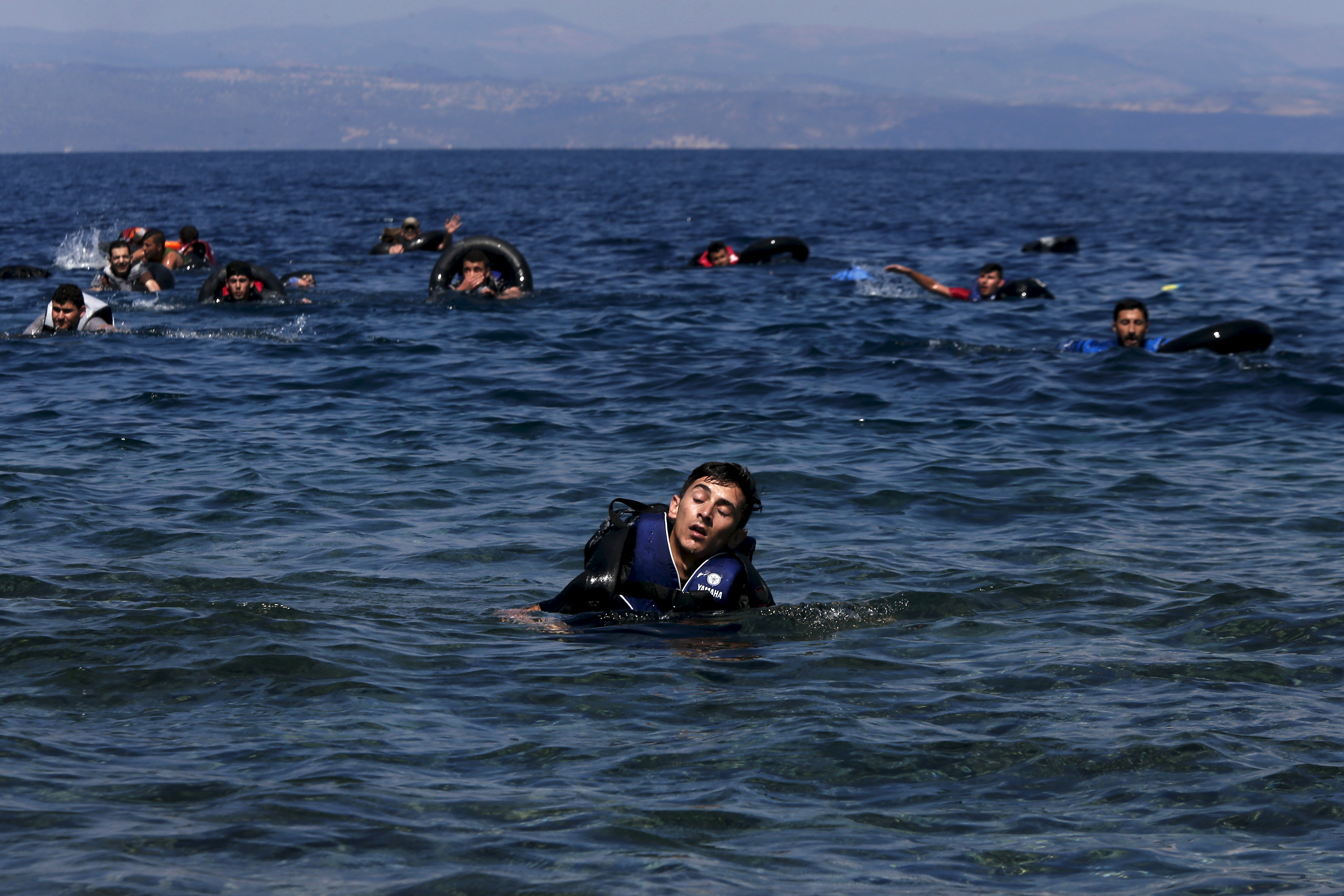 A refugee is seen swimming towards the shore near the Greek island of Lesbos