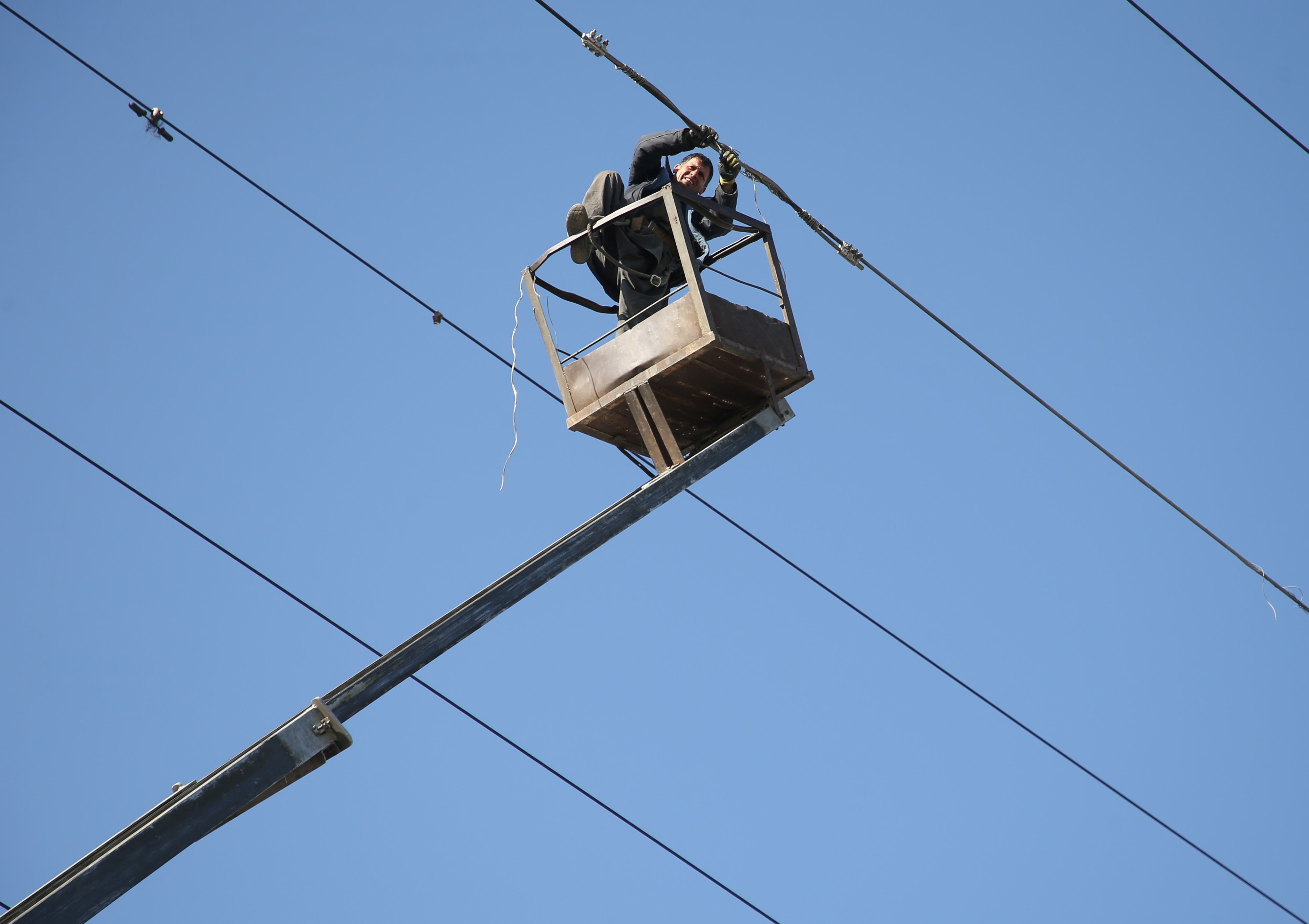 An Afghan man works on an electricity pole which was broken after a suicide bomb attack