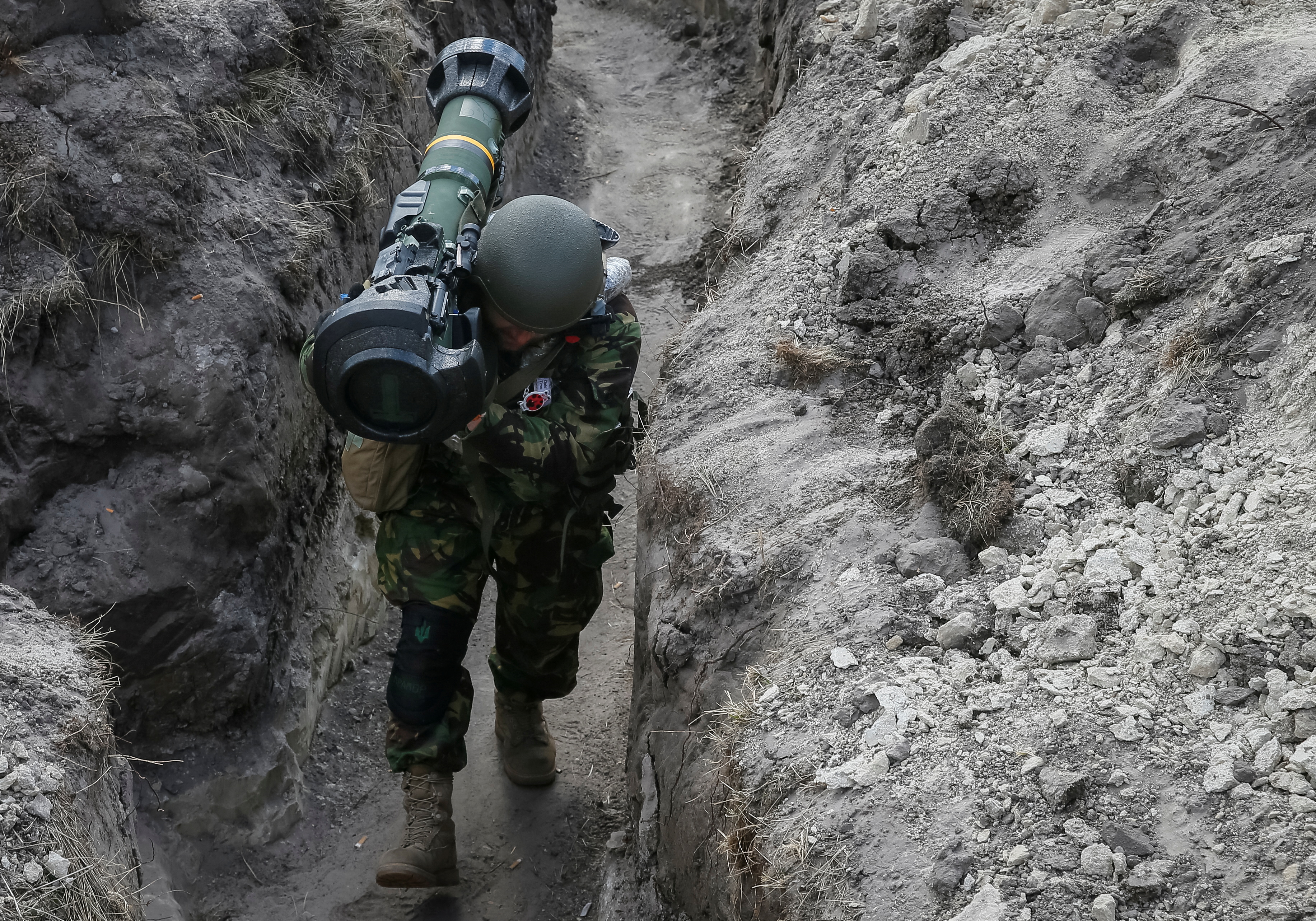 A Ukrainian service member walks along a trench with a next generation light anti-tank weapon in the north Kyiv region, Ukraine.