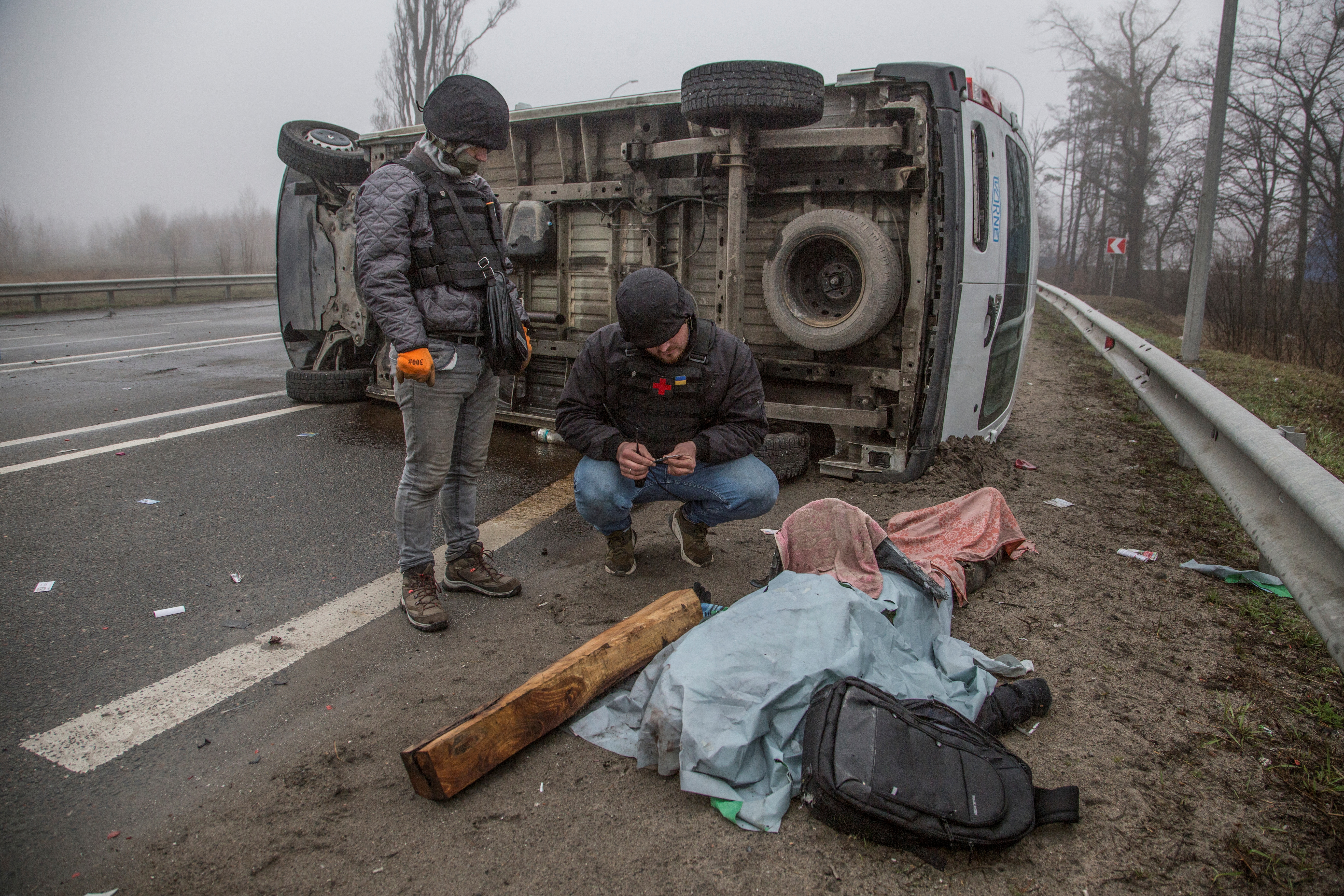 A volunteer inspects a body of a killed person