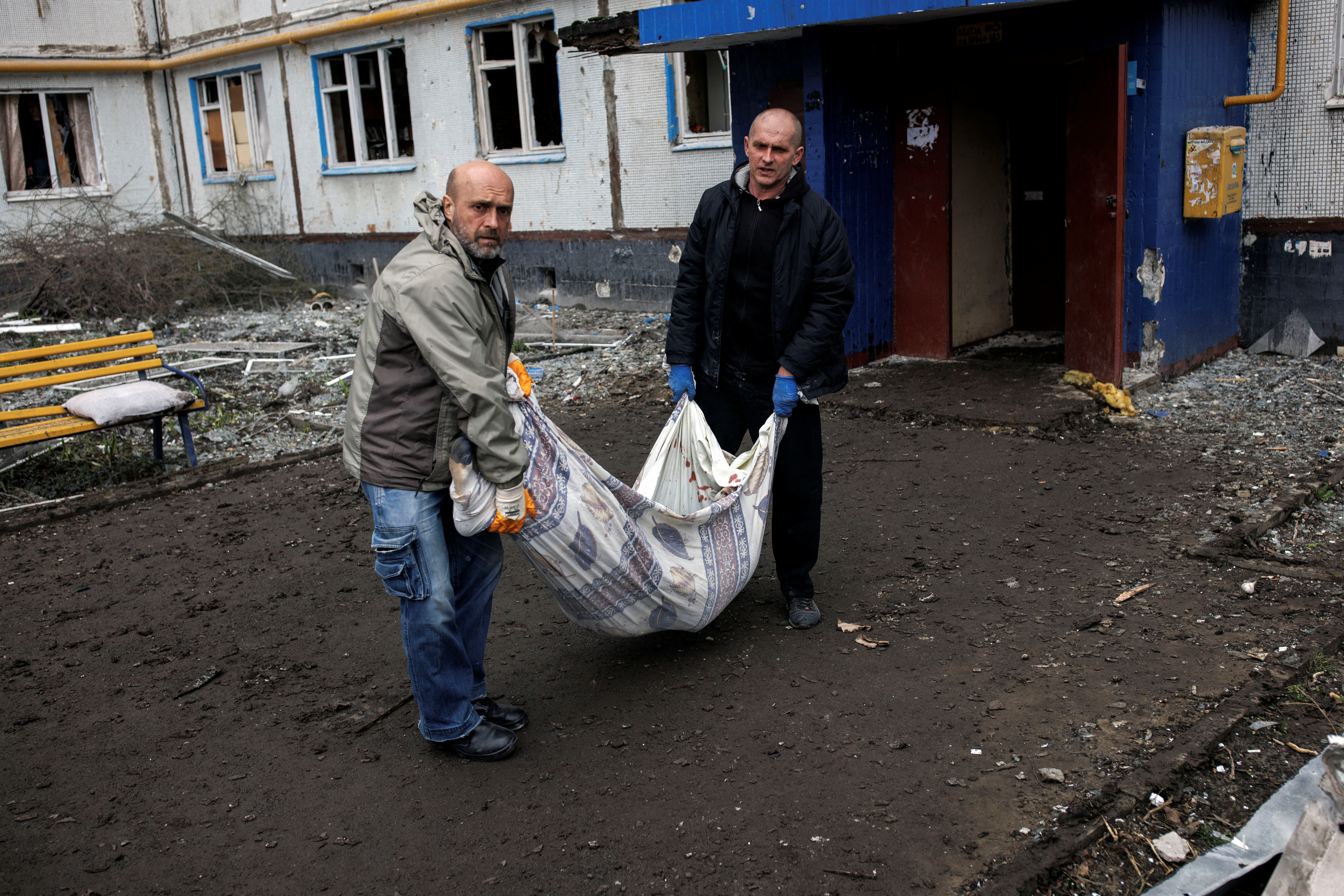 Emergency workers carry the body of local resident Sergiy, 41, from his destroyed apartment, following an artillery attack in Kharkiv, Ukraine. 