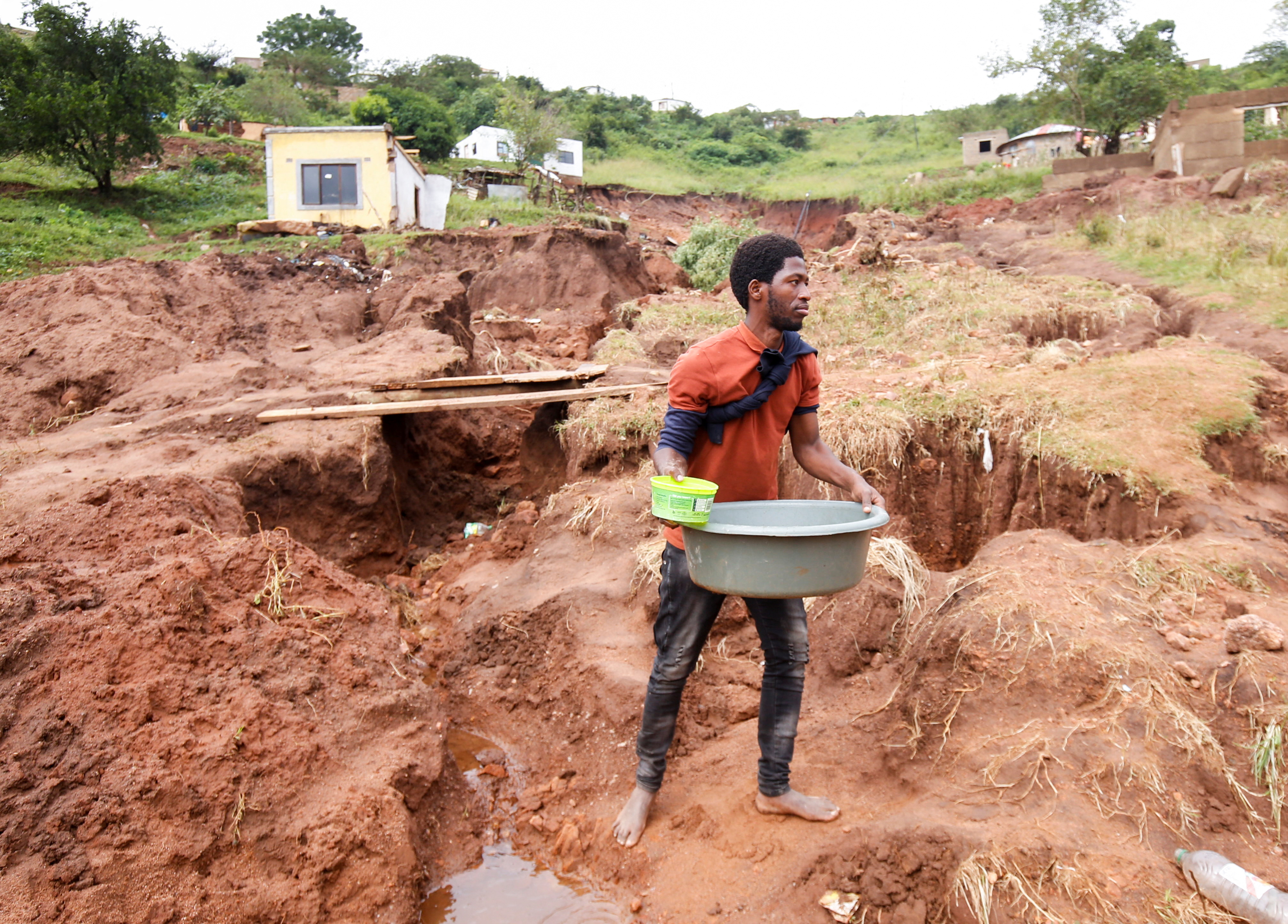 Mthandi Sibiya collects water near what remains of his home which collapsed while he was sleeping due flooding in Mzinyathi near Durban, South Africa,