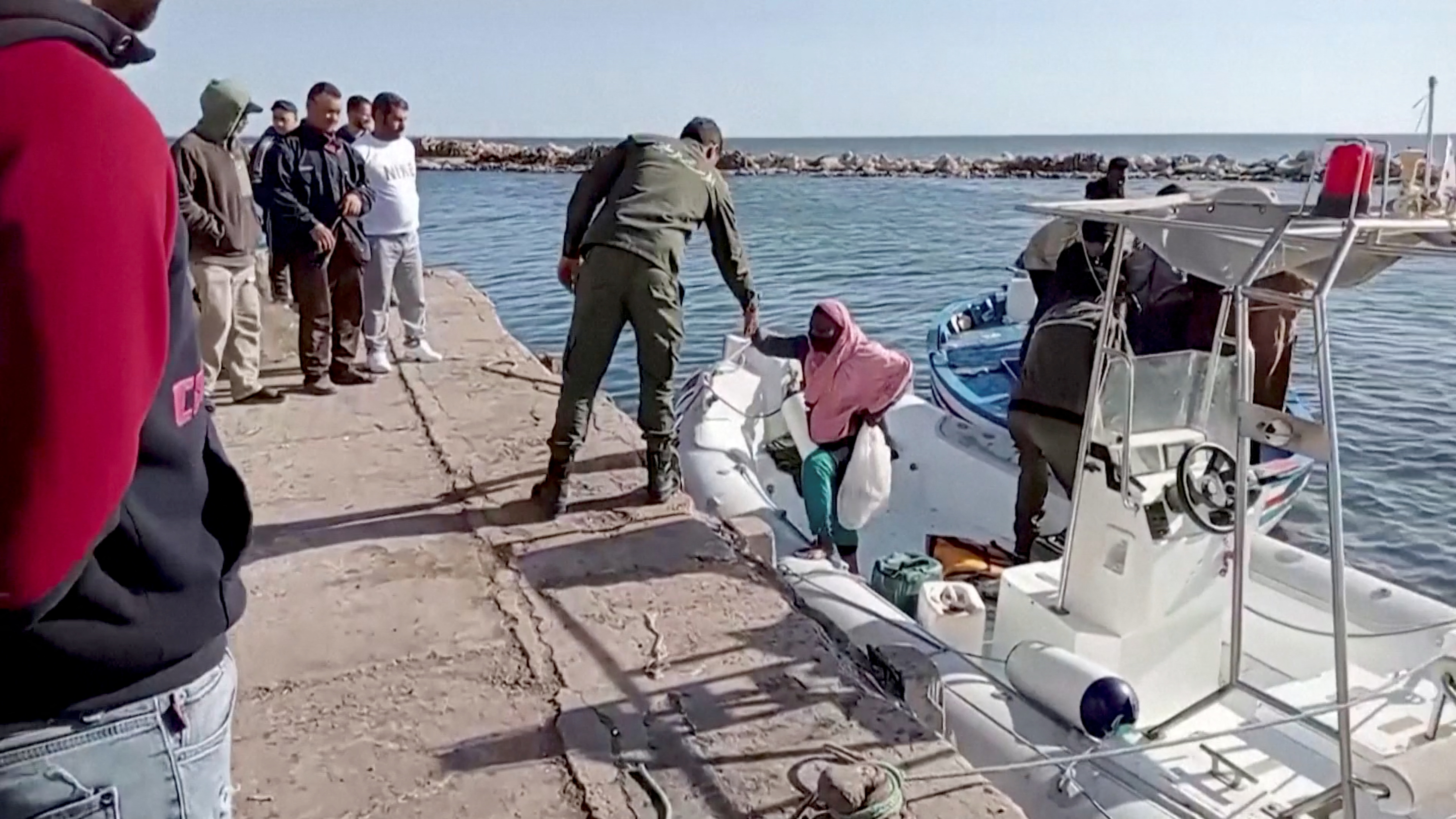 Man helps migrant off boat and onto shore