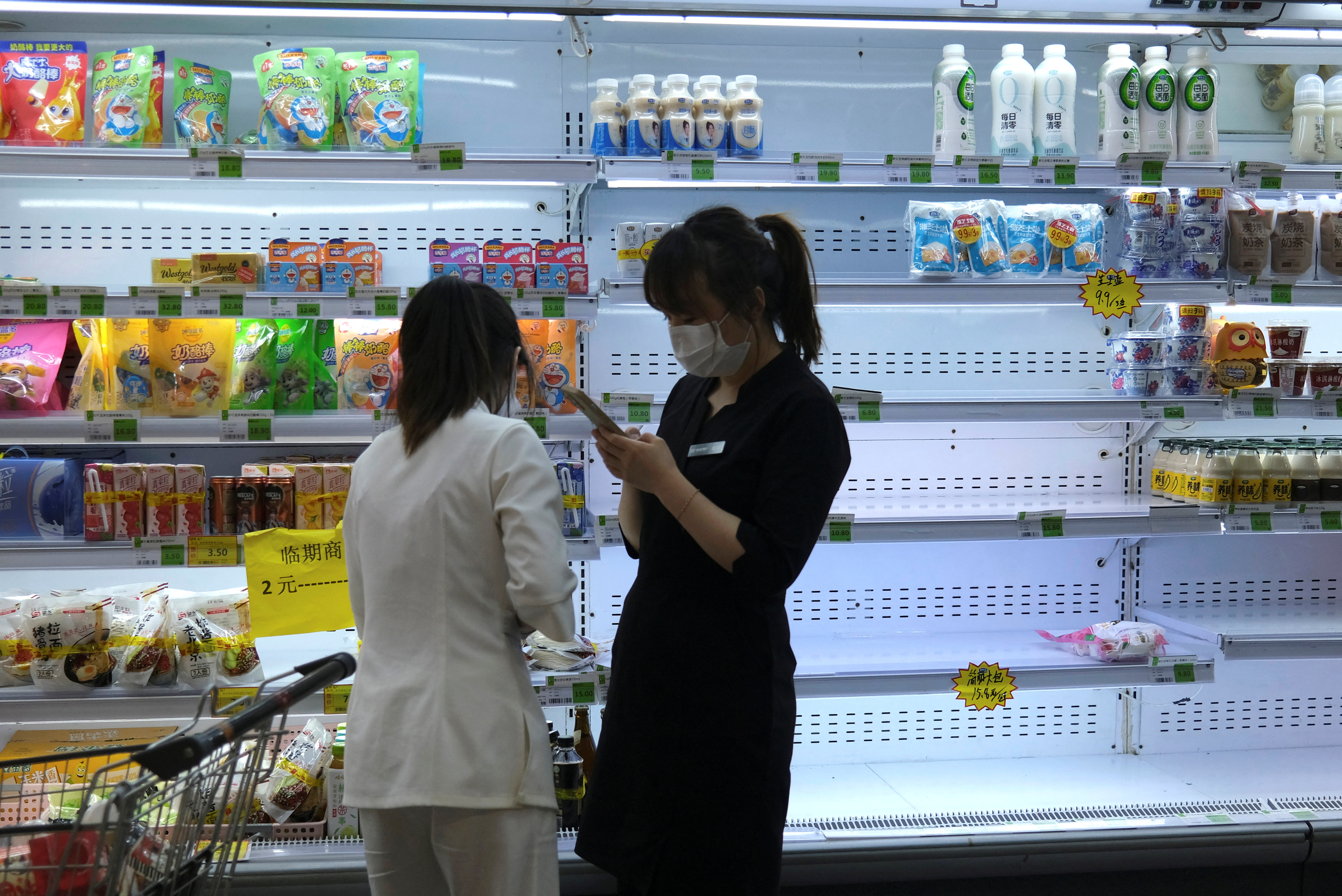 Customers shop in front of a half-empty freezer