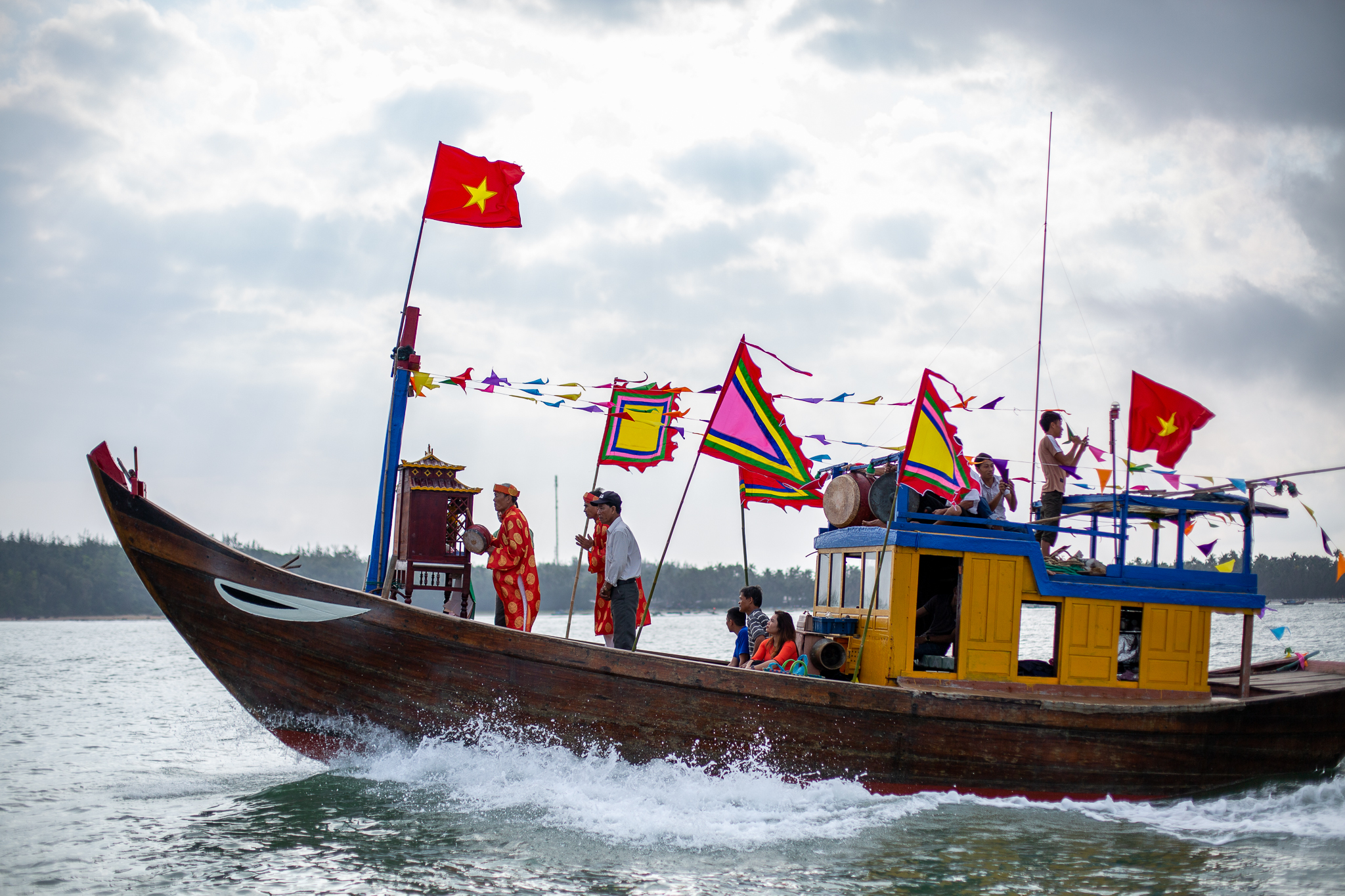 A photo of a a temple boat bedecked with brightly coloured bunting and an altar