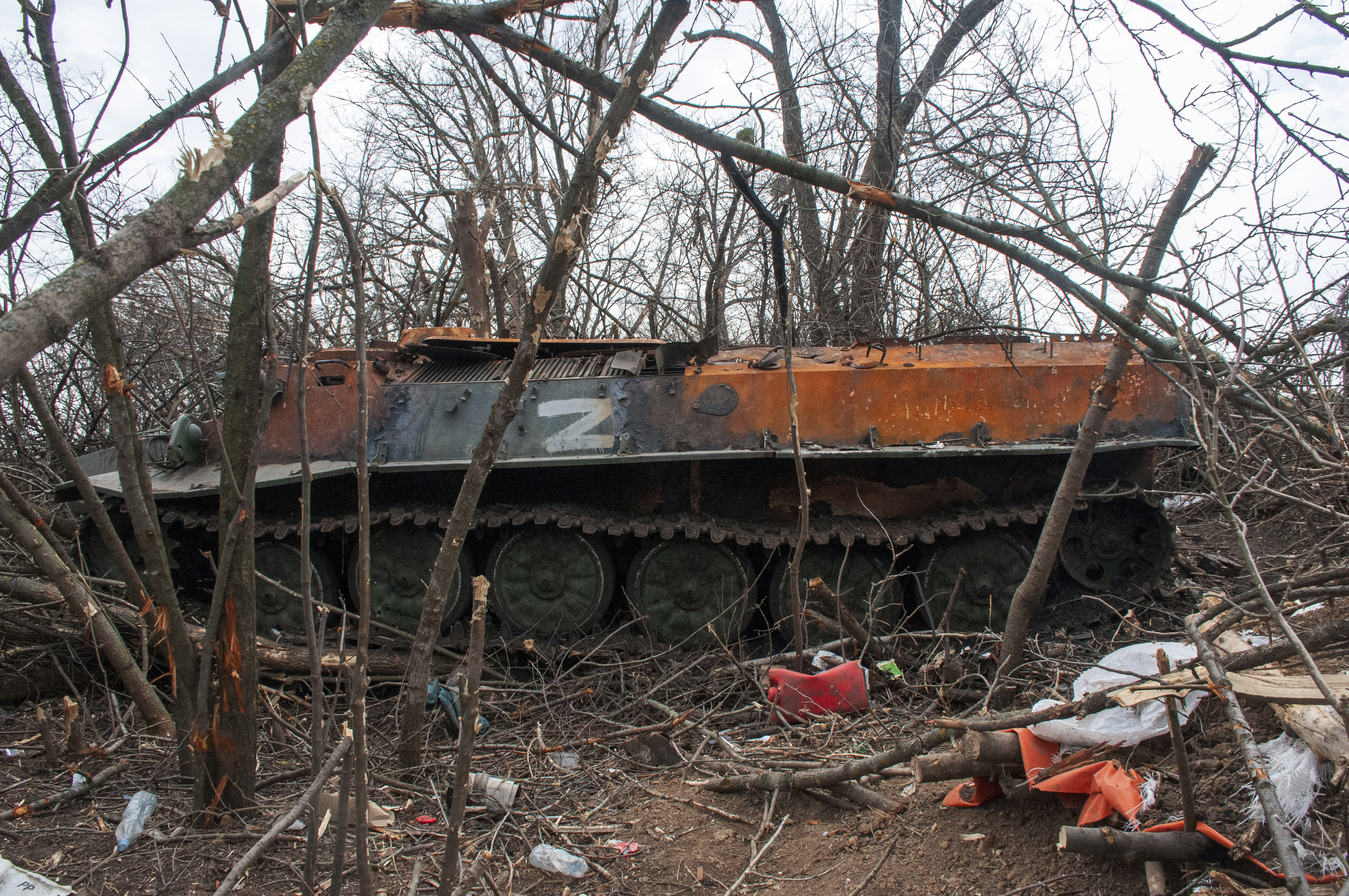 An armored vehicle sits destroyed in a field among bare trees near the village of Malaya Rohan