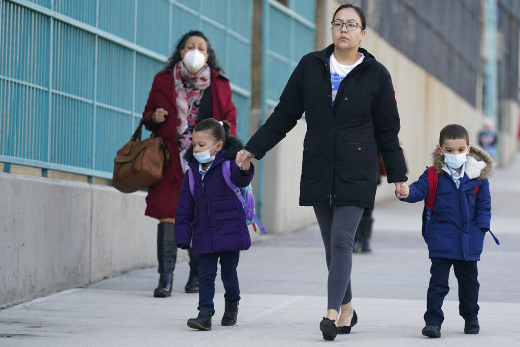 Masked children and their caregivers arrive for school in New York.