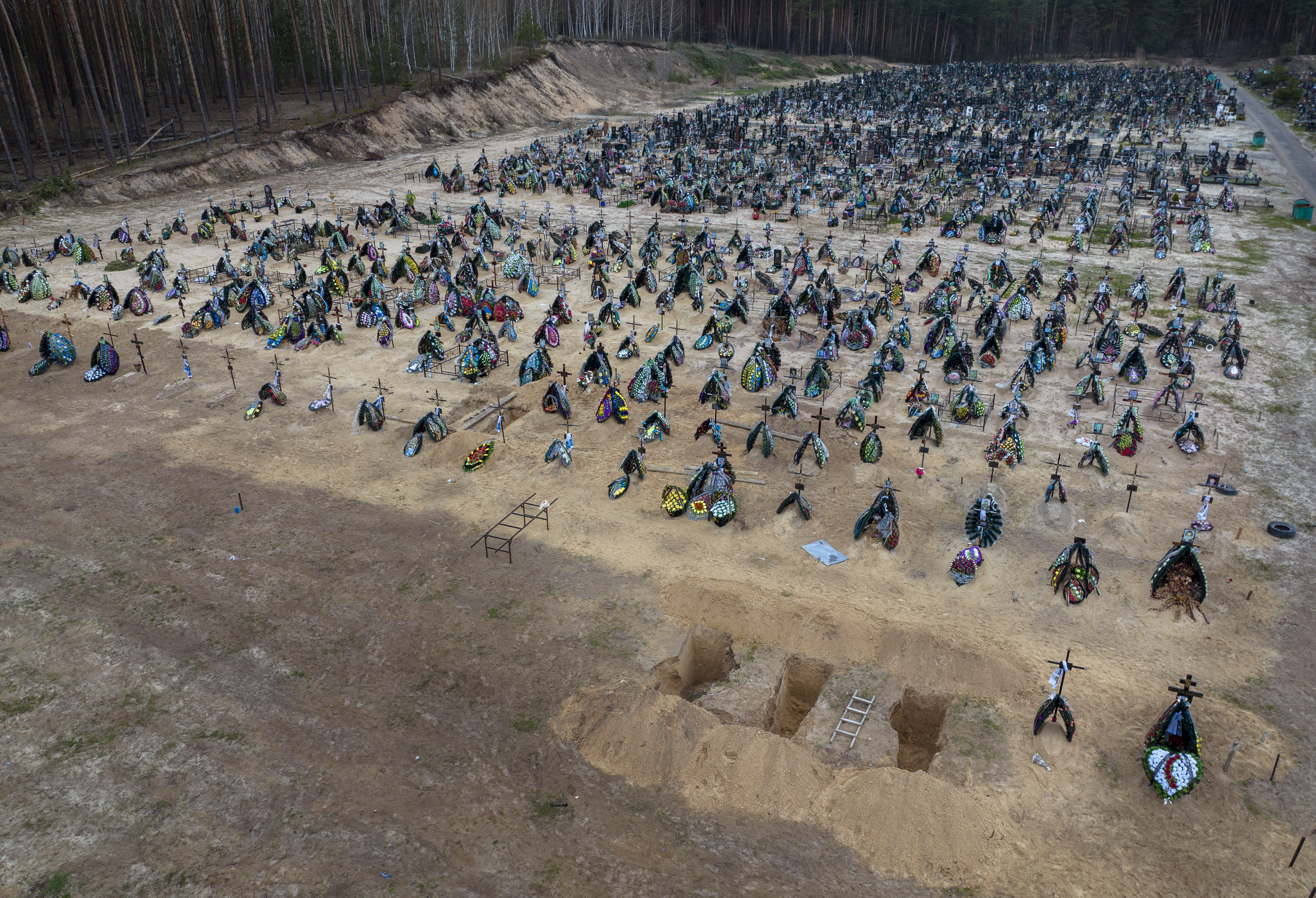 Three dug graves are ready for the next funerals at the cemetery in Irpin, on the outskirts of Kyiv, Ukraine, Tuesday, April 19, 2022.