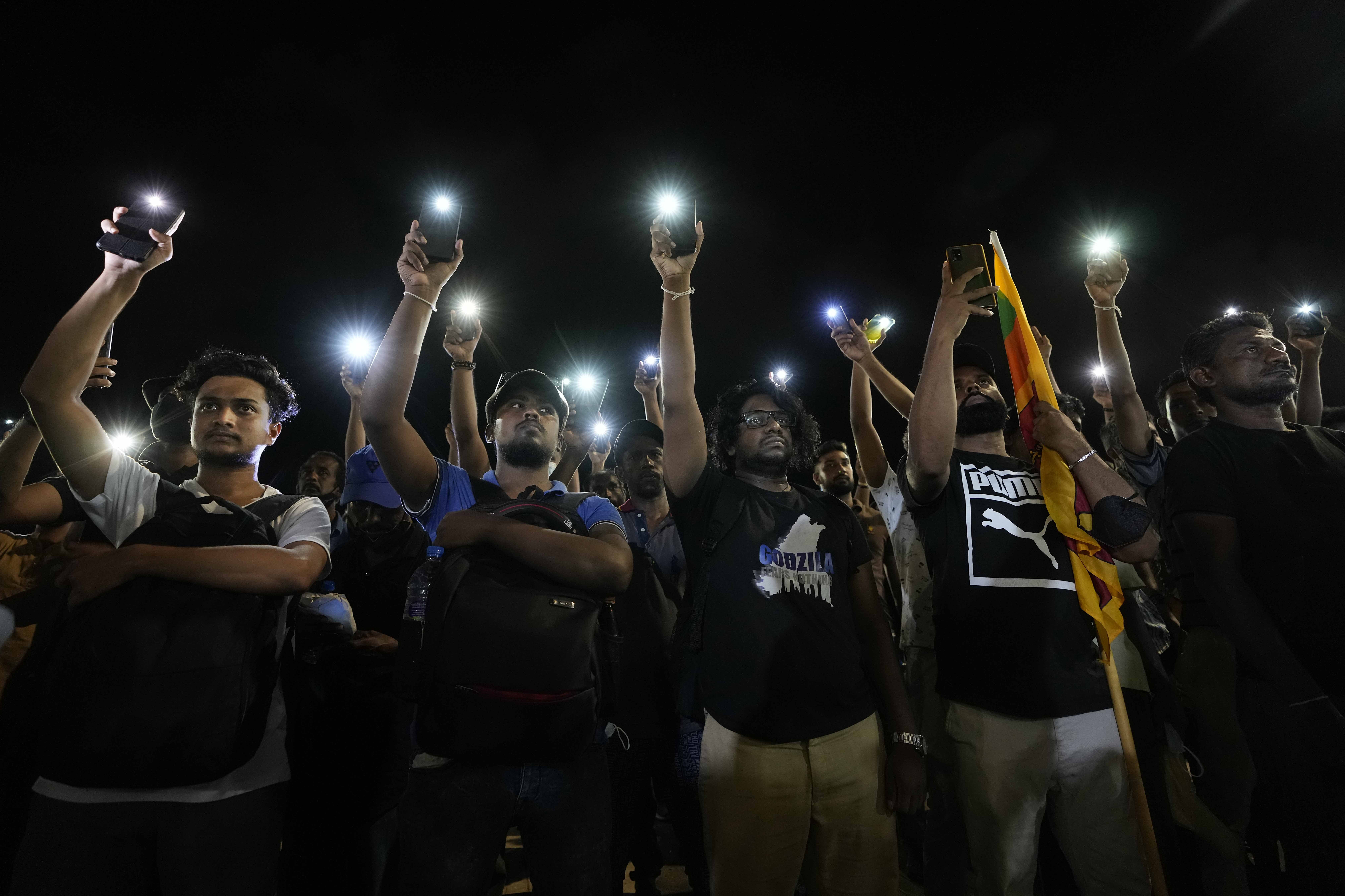 Sri Lankans hold up their mobile phone torches