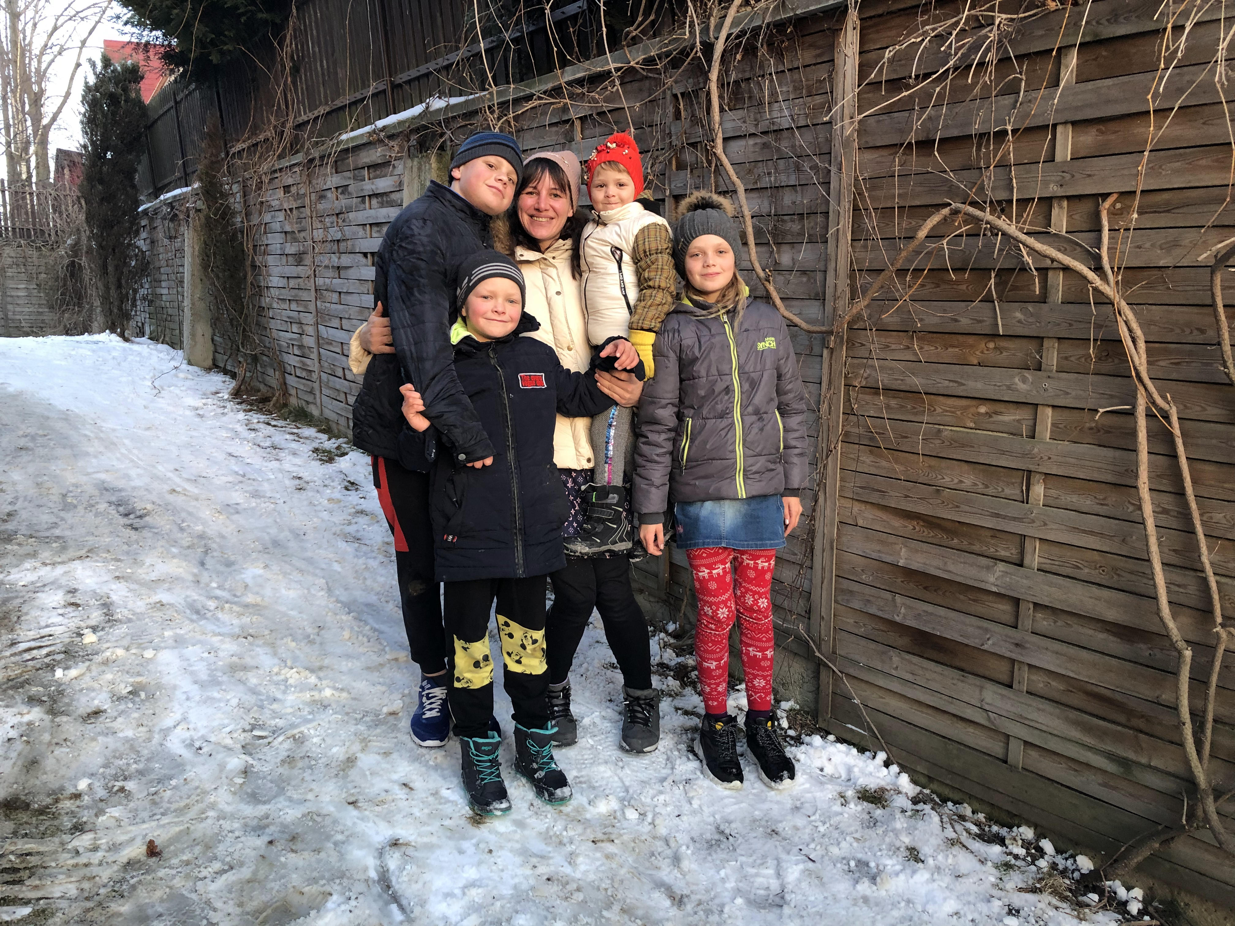 A photo of the Grichuk family standing outside in the snow with a woman and four children around her.