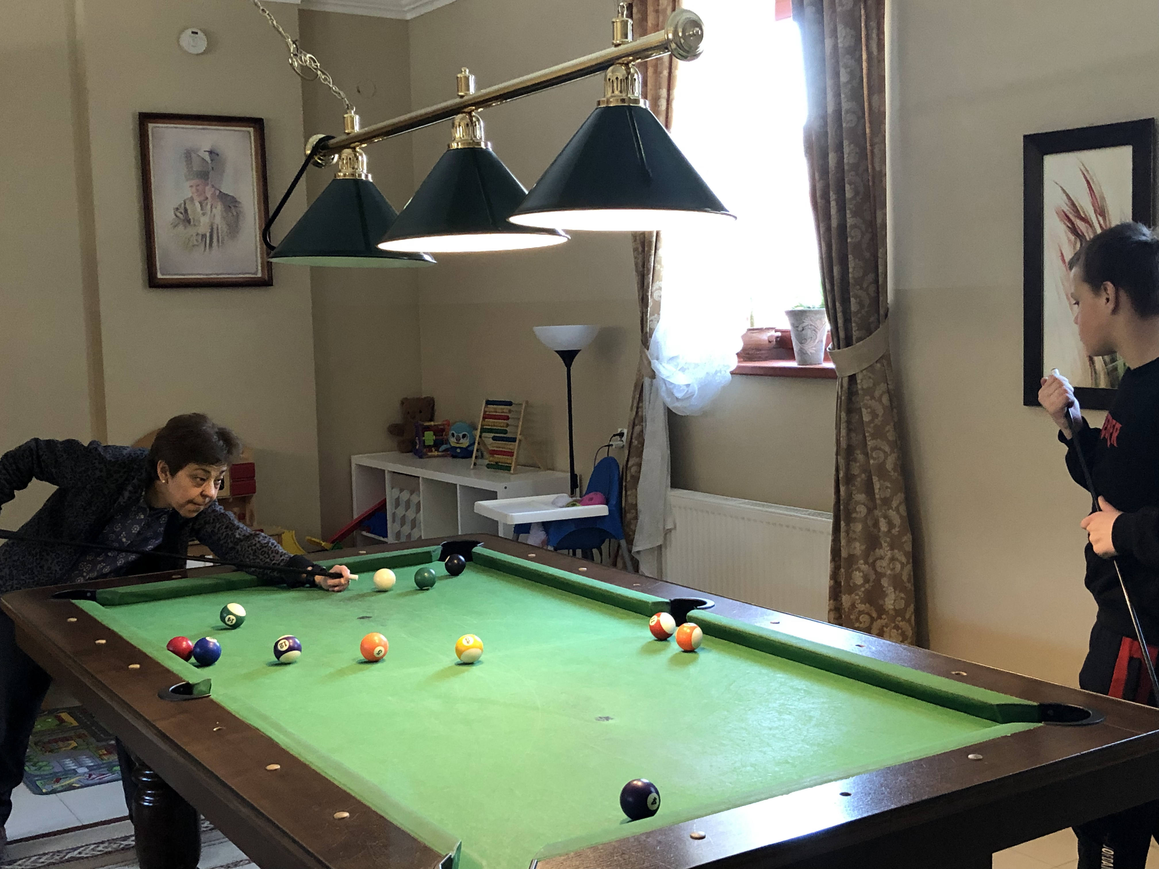 A photo of One of the Grichuk children playing billiards with a volunteer.