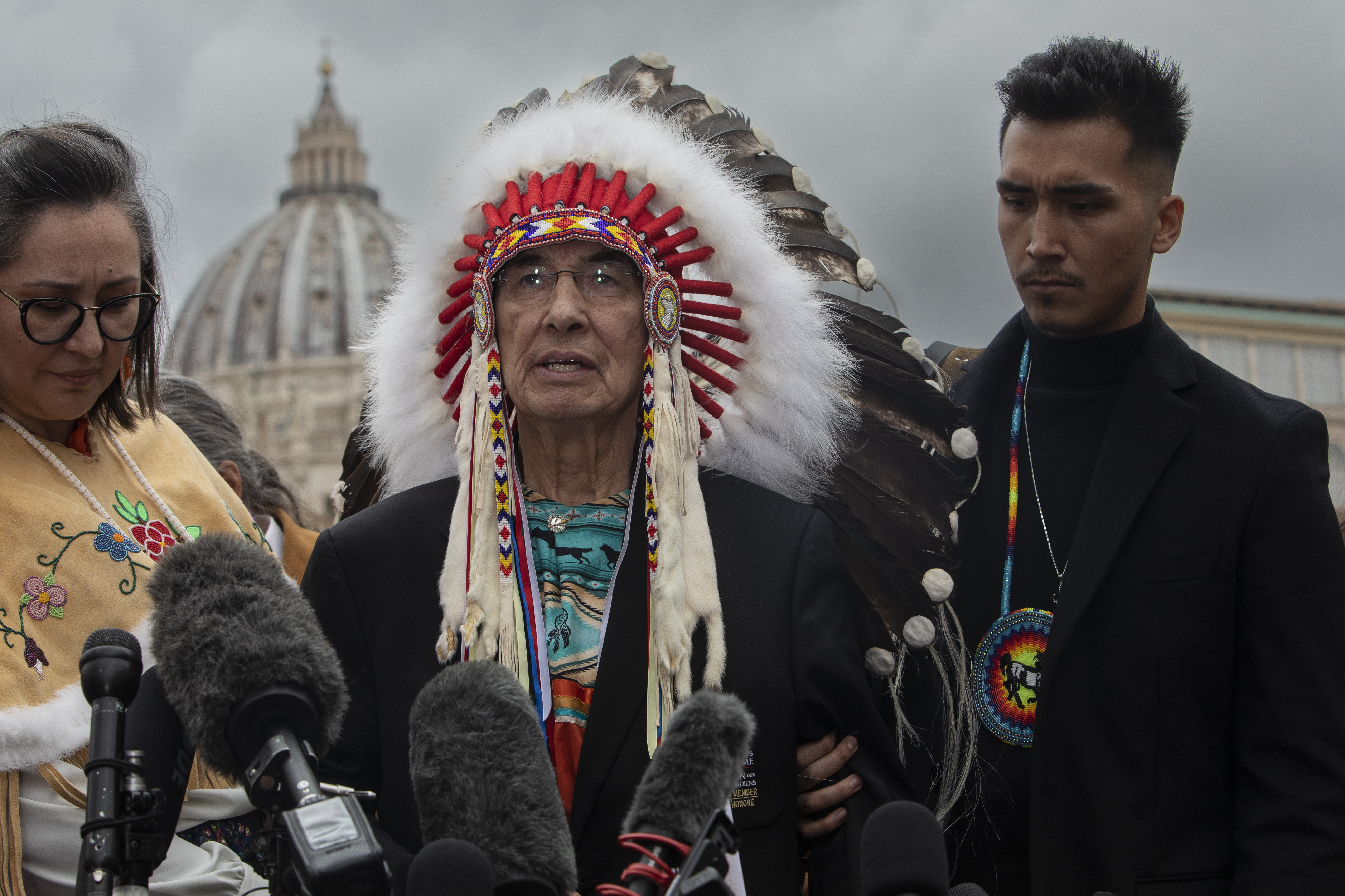 A photo of Wilton Littlechild speaking into reporter microphones.
